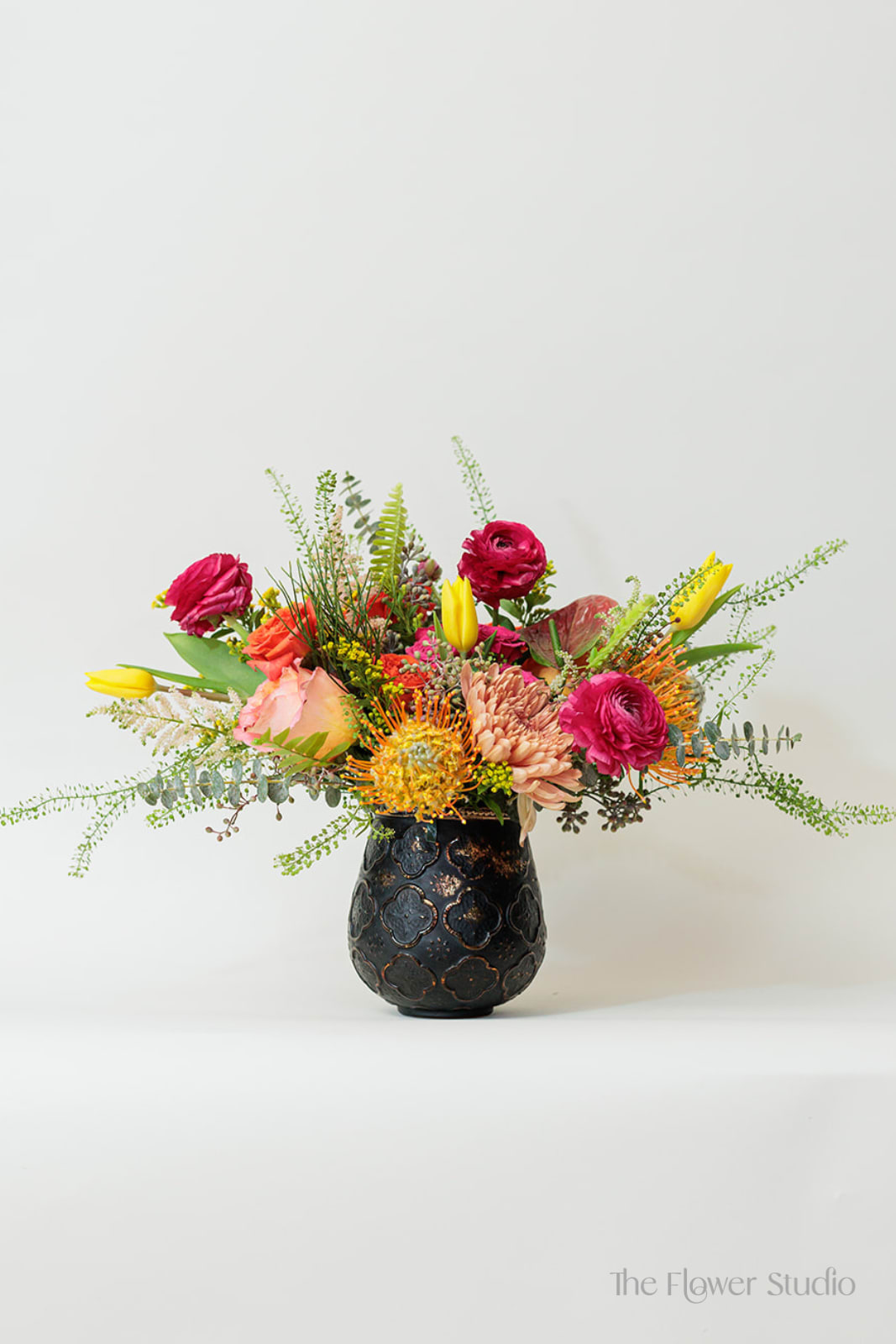 Colorful mixed flower arrangement in a dark decorative vase