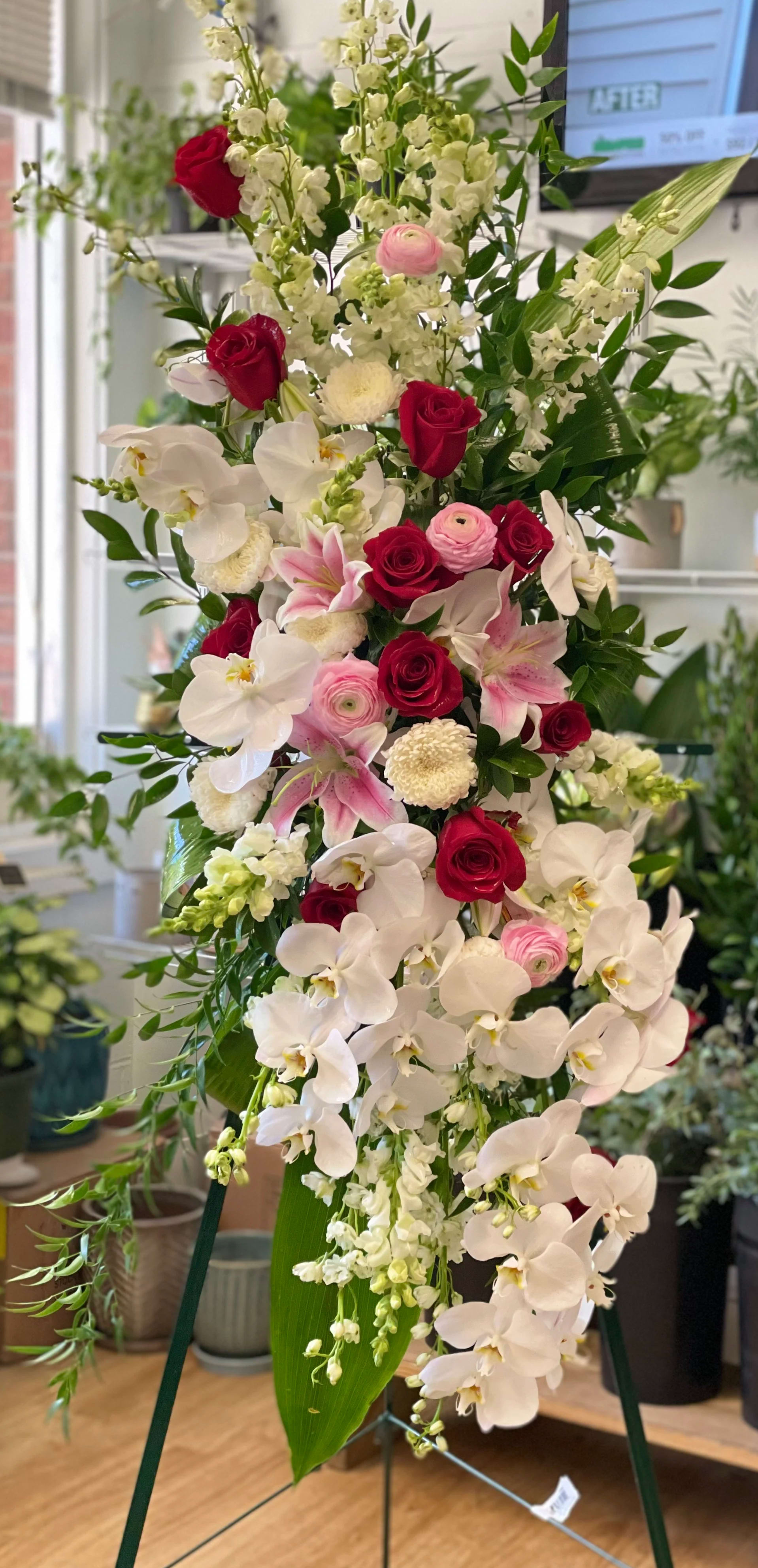 Tall floral standing spray with white orchids, red roses, and pink blooms