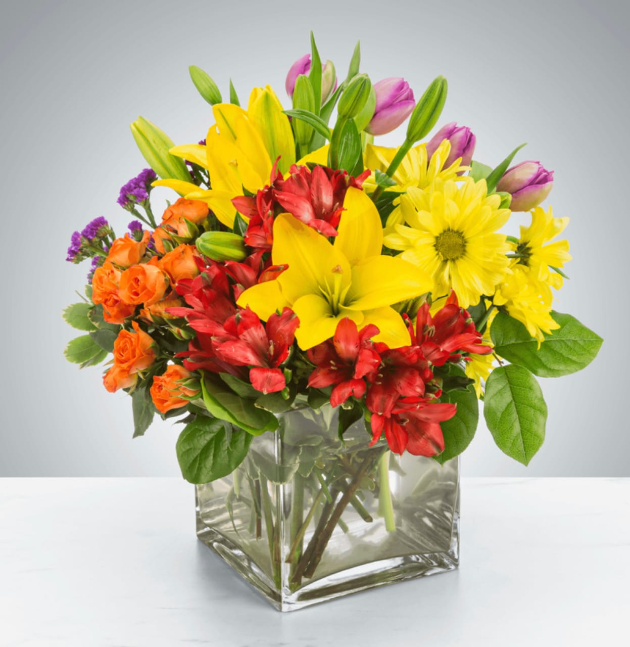 Juicy  - Juicy packs a color punch! Featuring over 6 different flowers and greens, all in different colors, this arrangement is a great option for sending to co-workers, friends, or clients. Make a brightly colored splash.  Approximate Dimensions: 12"D x 12"H