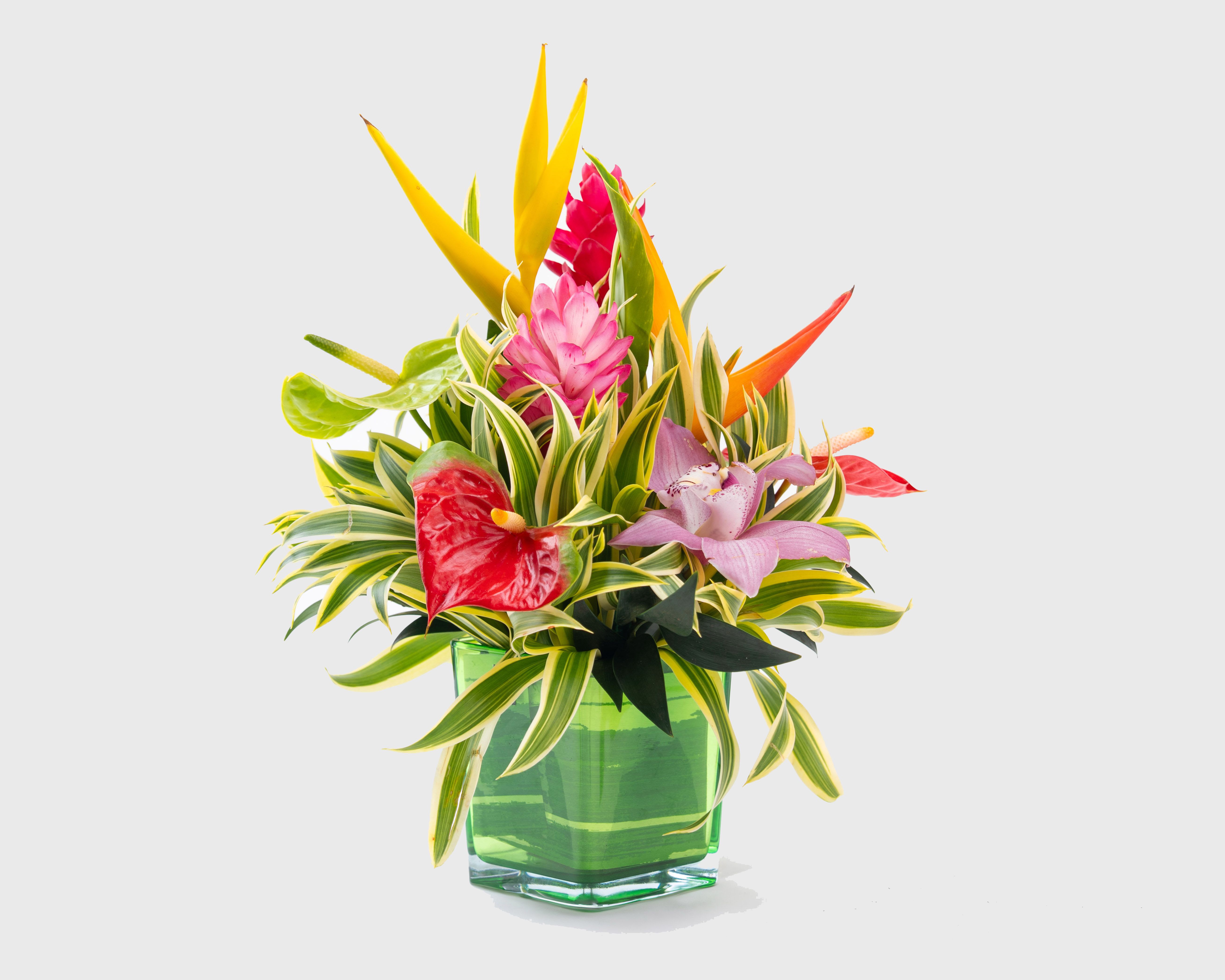 Tropical flower arrangement in a green glass vase with pink and yellow blooms
