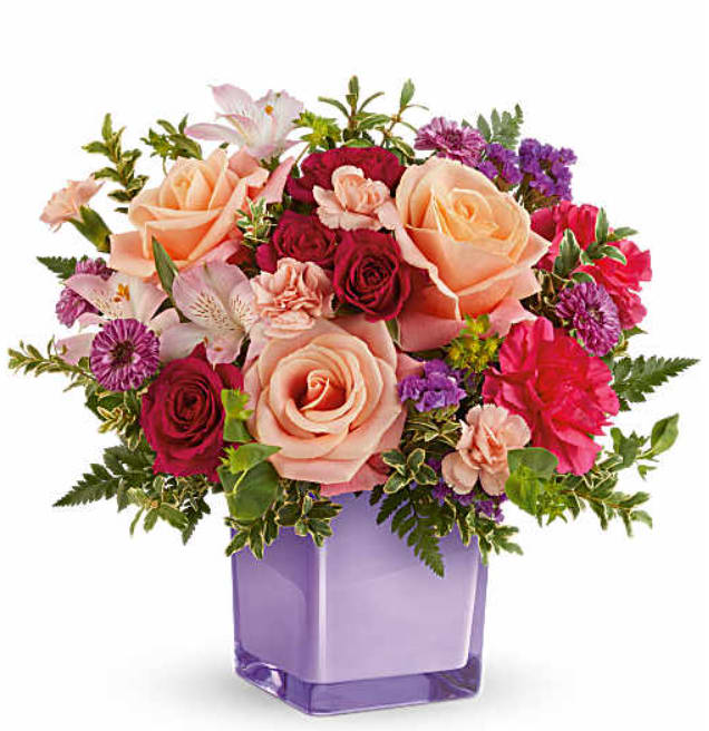 TF Sunset Sorbet Bouquet - Teleflora's Sunset Sorbet Bouquet includes peach roses, hot pink spray roses, light pink alstroemeria, hot pink carnations, peach miniature carnations, purple button spray chrysanthemums, and purple statice. Presented in an amethyst-colored glass cube vase.