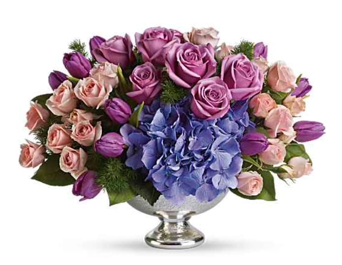 TF Purple Elegance Centerpiece - Lovely lavender roses, light pink spray roses, purple tulips and brilliant blue hydrangea are accented with fresh greens.