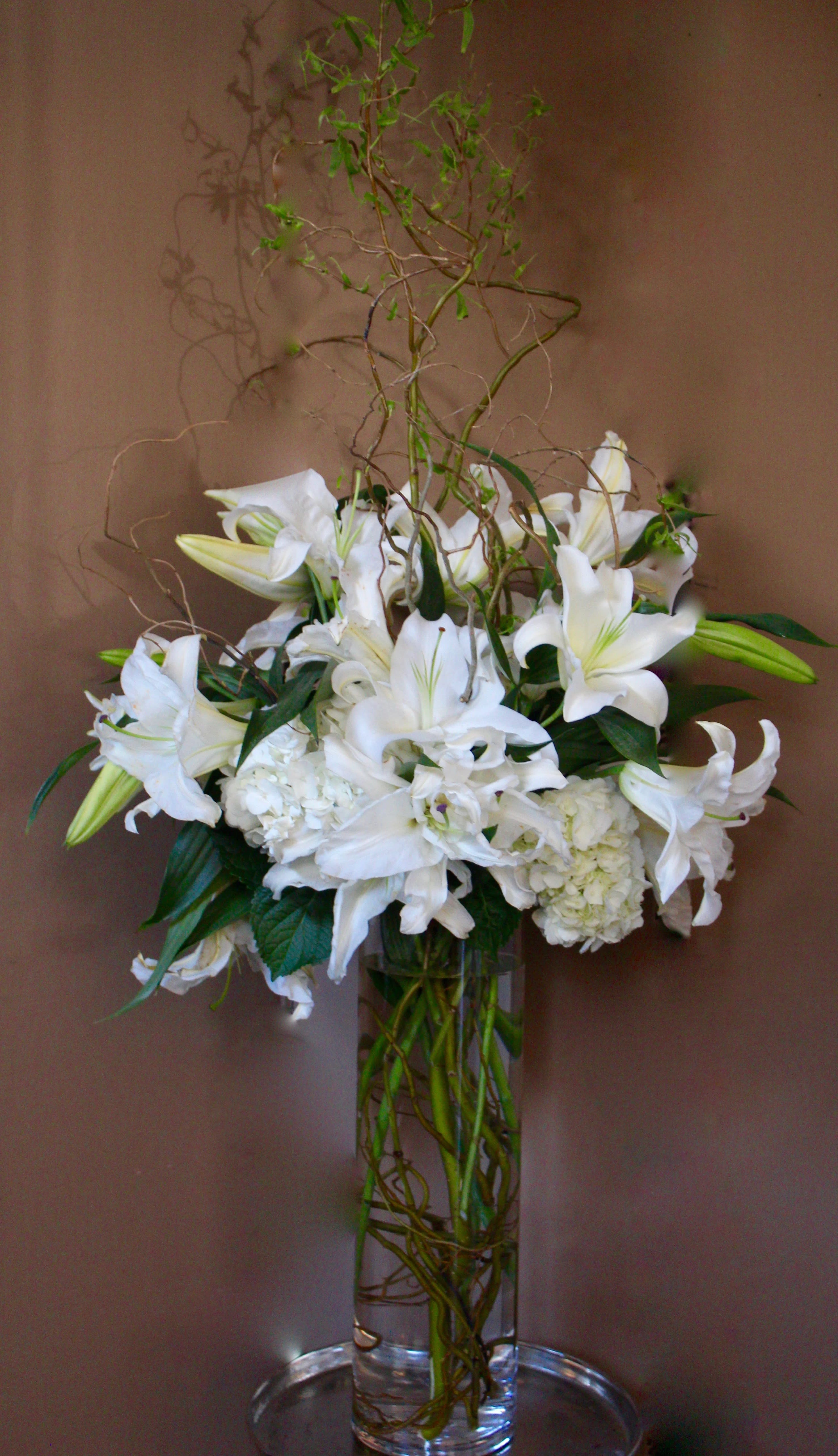 White lilies and hydrangeas in a tall glass vase
