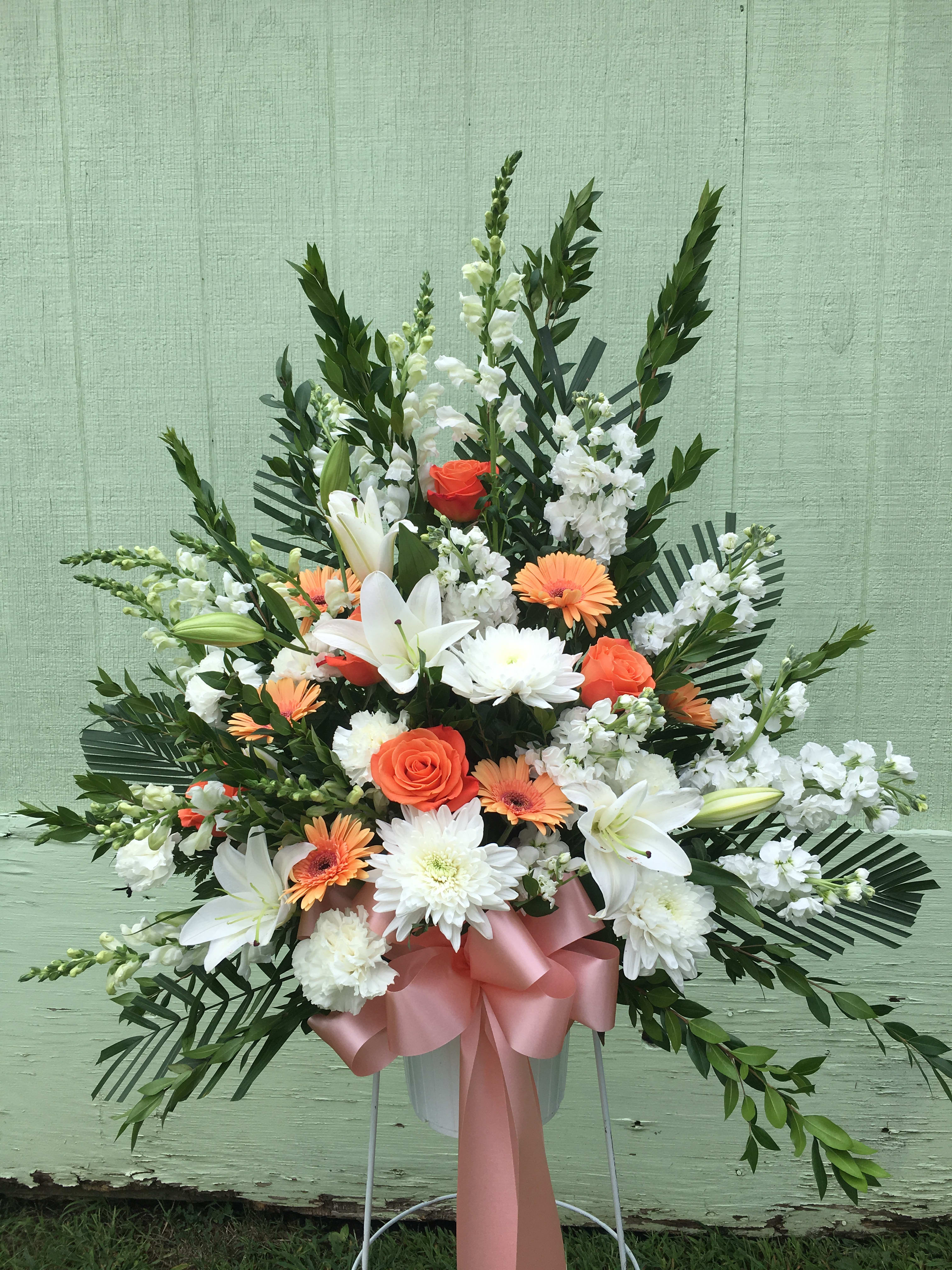 Standing floral spray with white lilies, orange roses, and white daisies