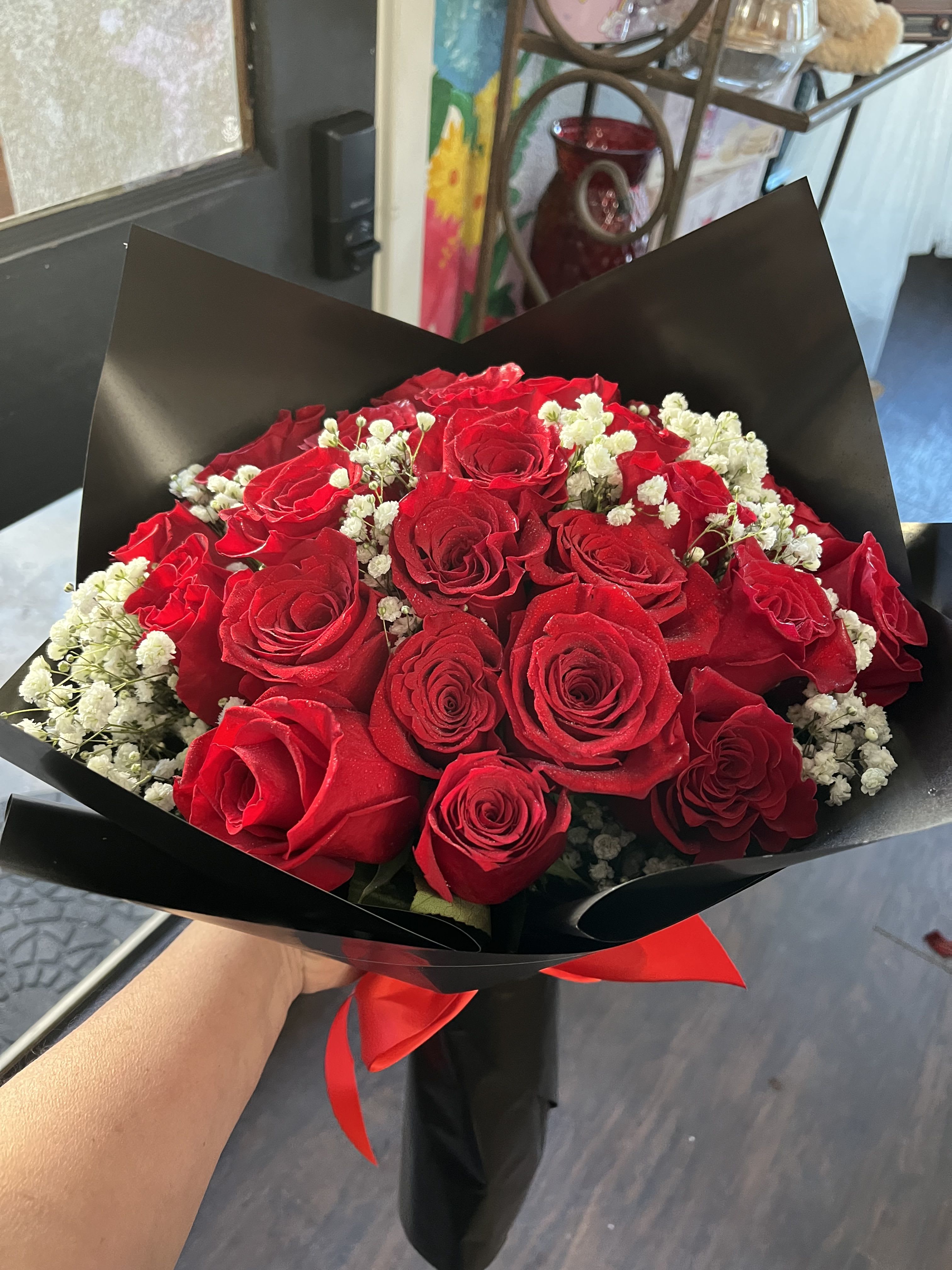 Bouquet of red roses with white baby's breath in black wrap