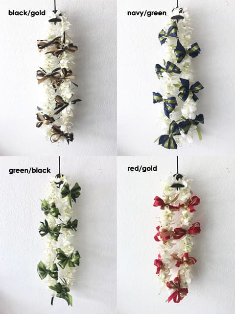 Four white floral leis with ribbon bows in different color combinations