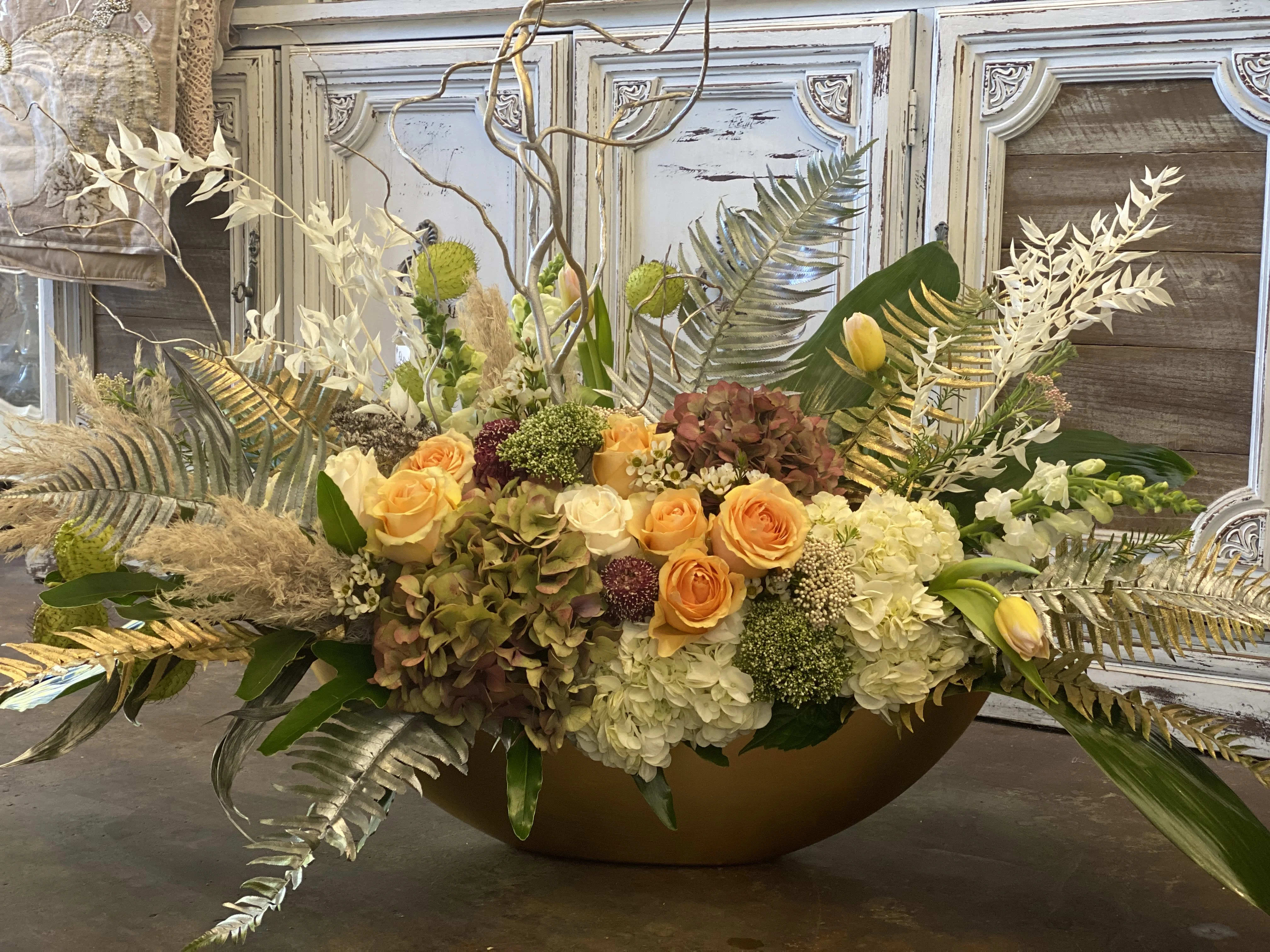Large floral centerpiece with orange roses and white hydrangeas in a low bowl