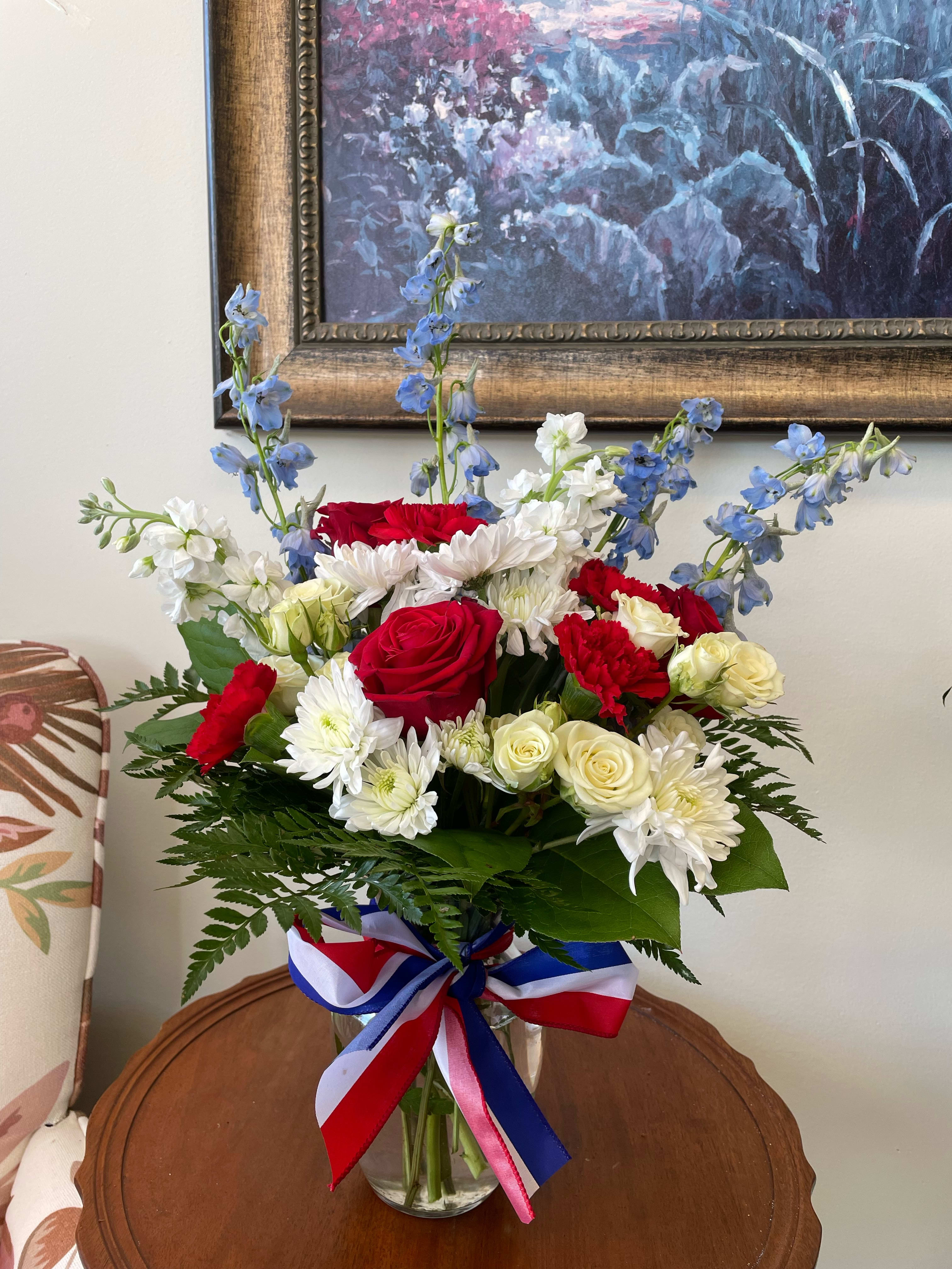 Admirable Duty - This patriotic arrangement features blooms such as delphinium, roses, and carnations. Perfect for Memorial Day, Veteran's Day, or Fourth of July.