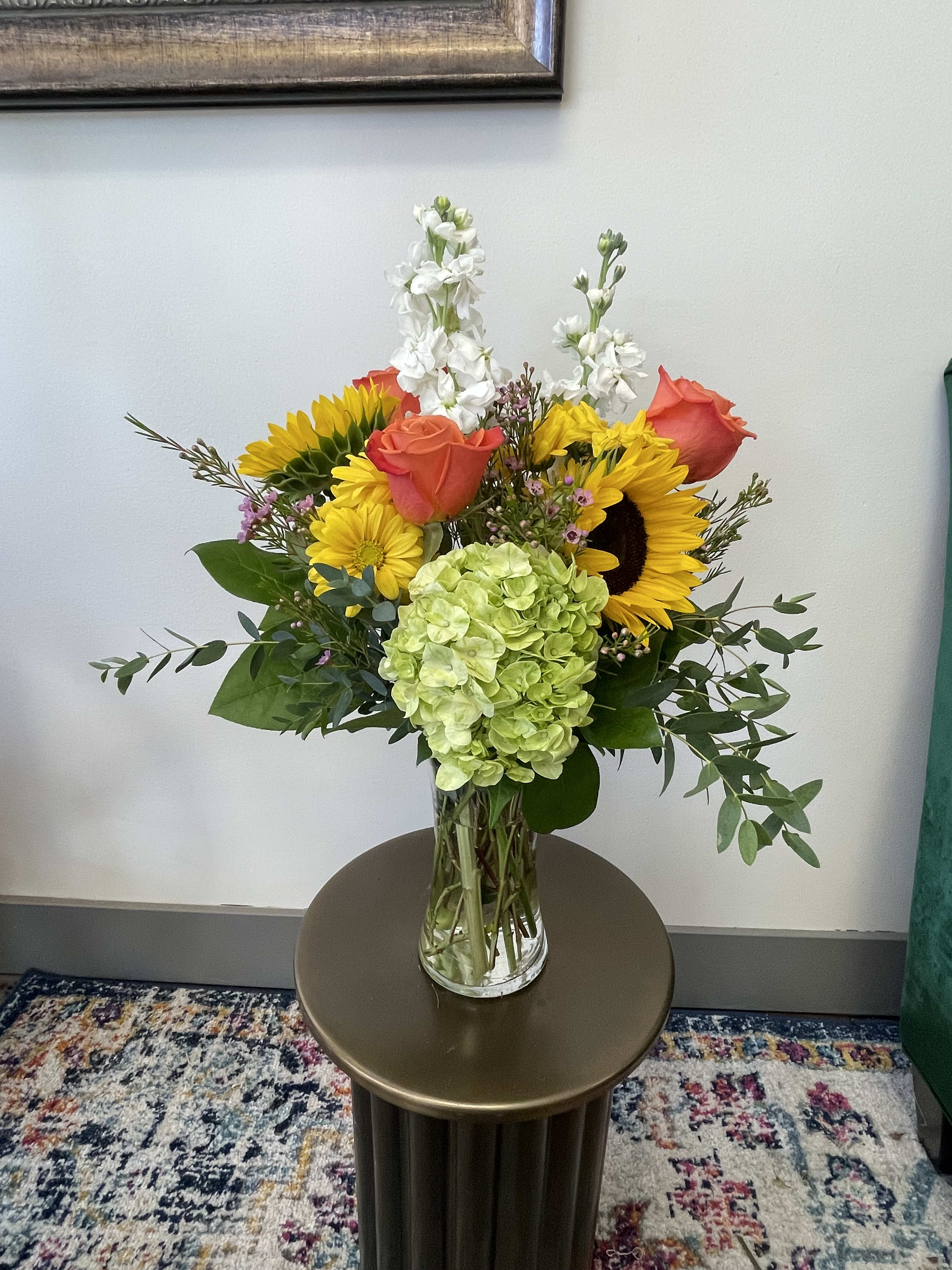 Autumn Days - This autumnal arrangement features blooms such as sunflowers, orange roses, daisies, and more! Perfect for any occasion this fall season.