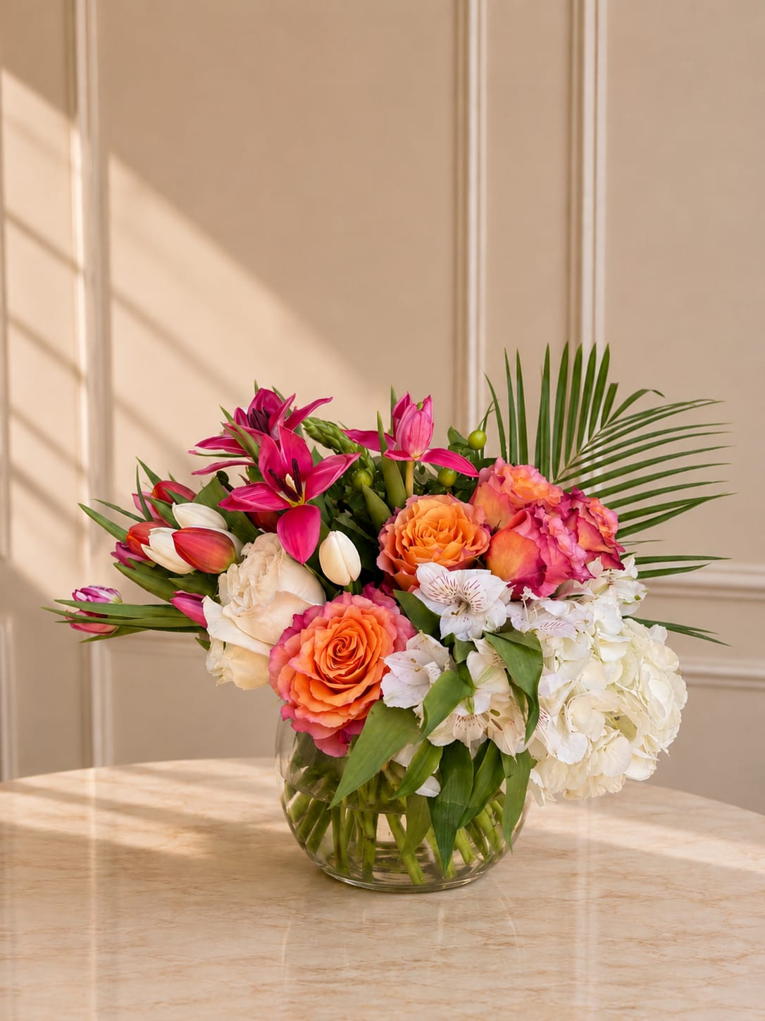     Paradise Petals - Soft pink and peach blooms arranged in a clear glass vase with fresh seasonal greenery.
