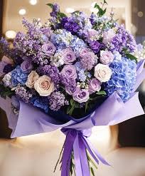 Lavender and blue bouquet of roses and hydrangeas wrapped in purple paper
