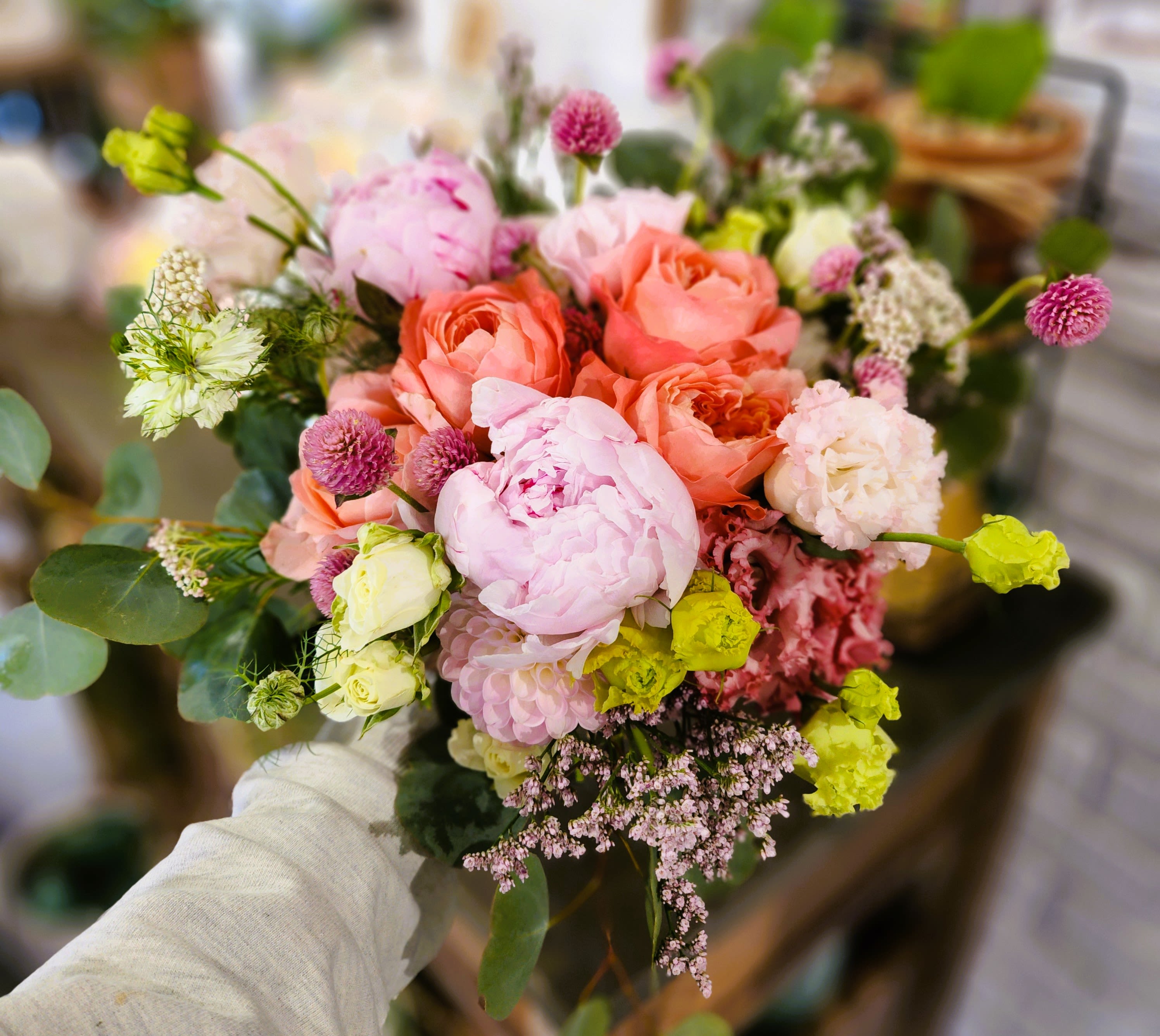 Handheld bouquet of pink and peach flowers with small accent blooms