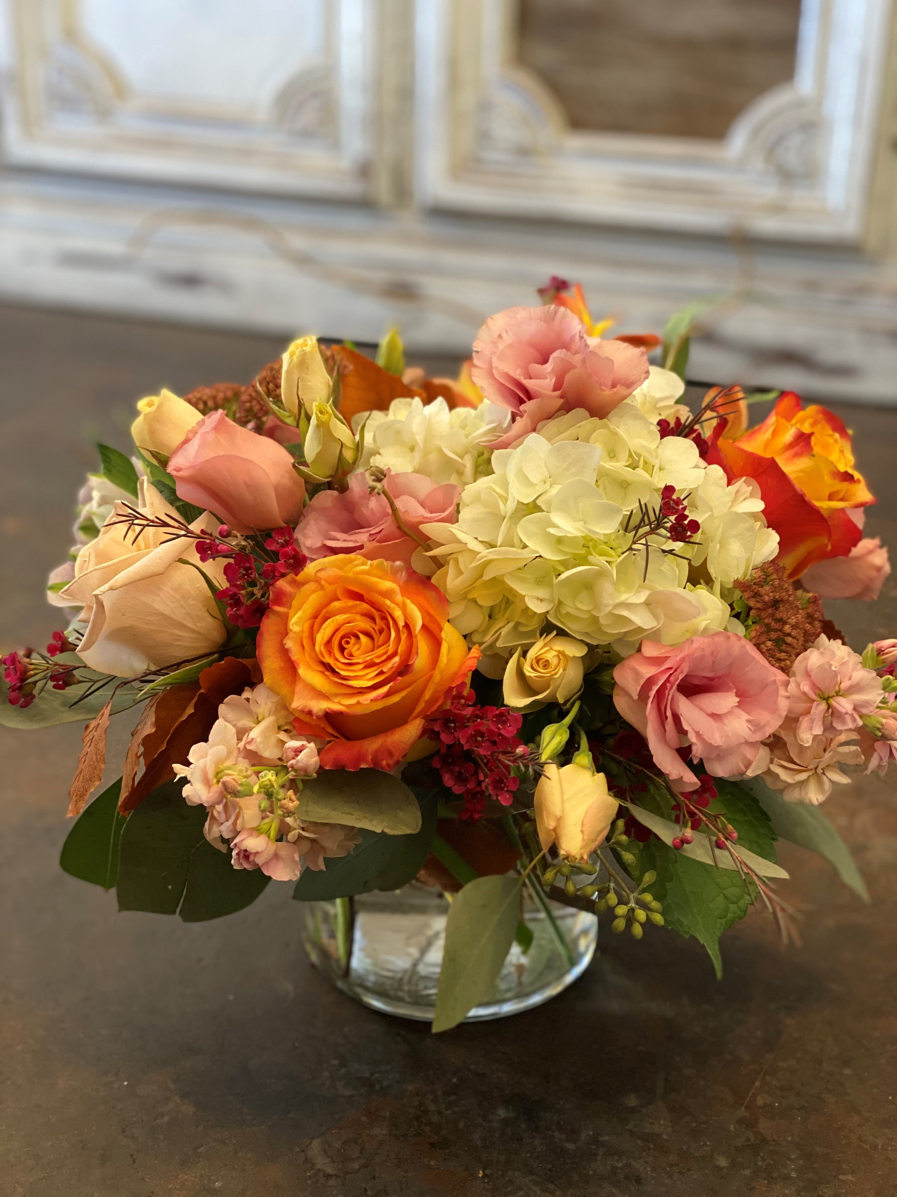 Mixed bouquet of roses, hydrangeas, and pink blooms in a glass vase