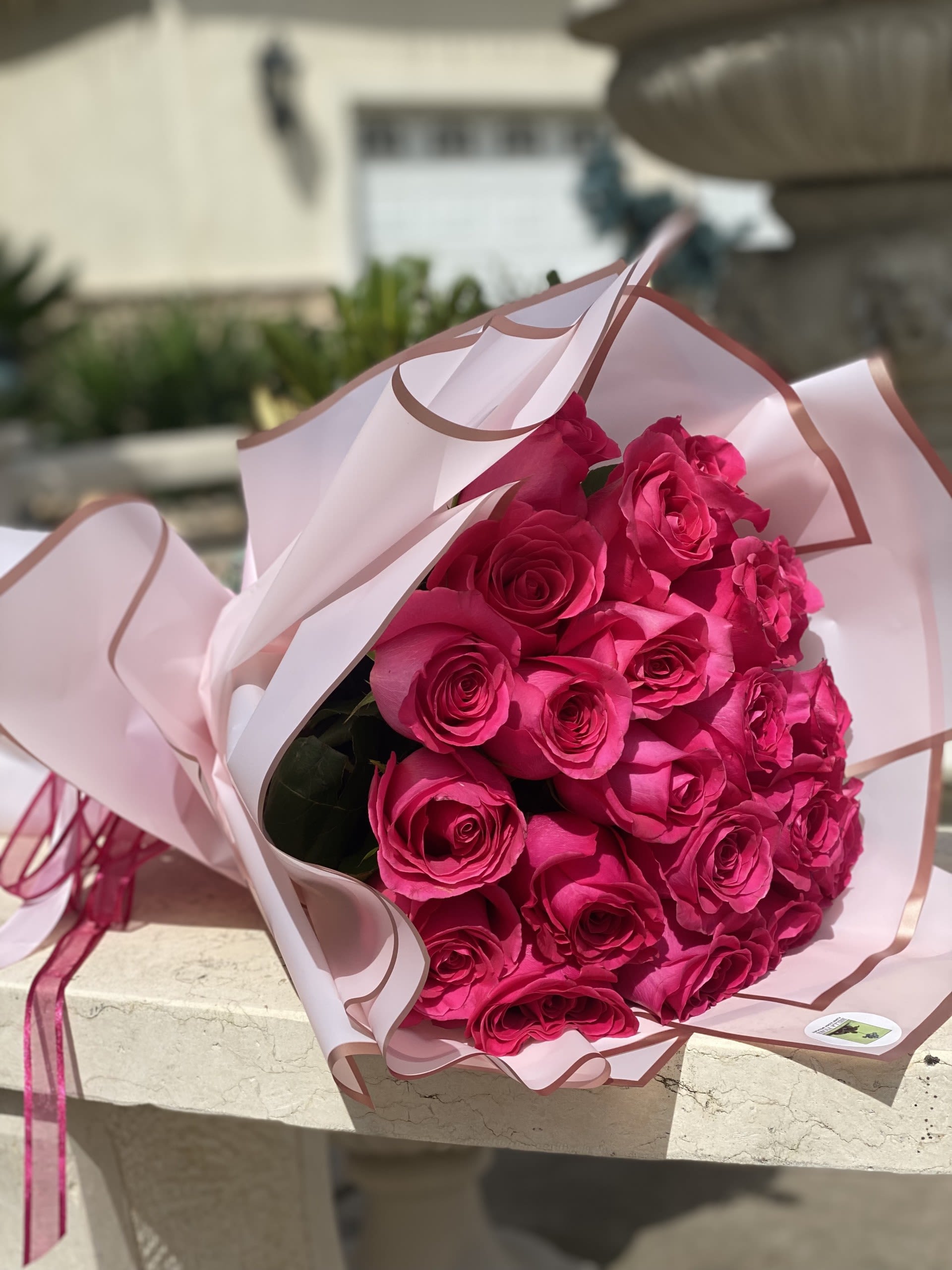 Bouquet of bright pink roses wrapped in pale pink paper