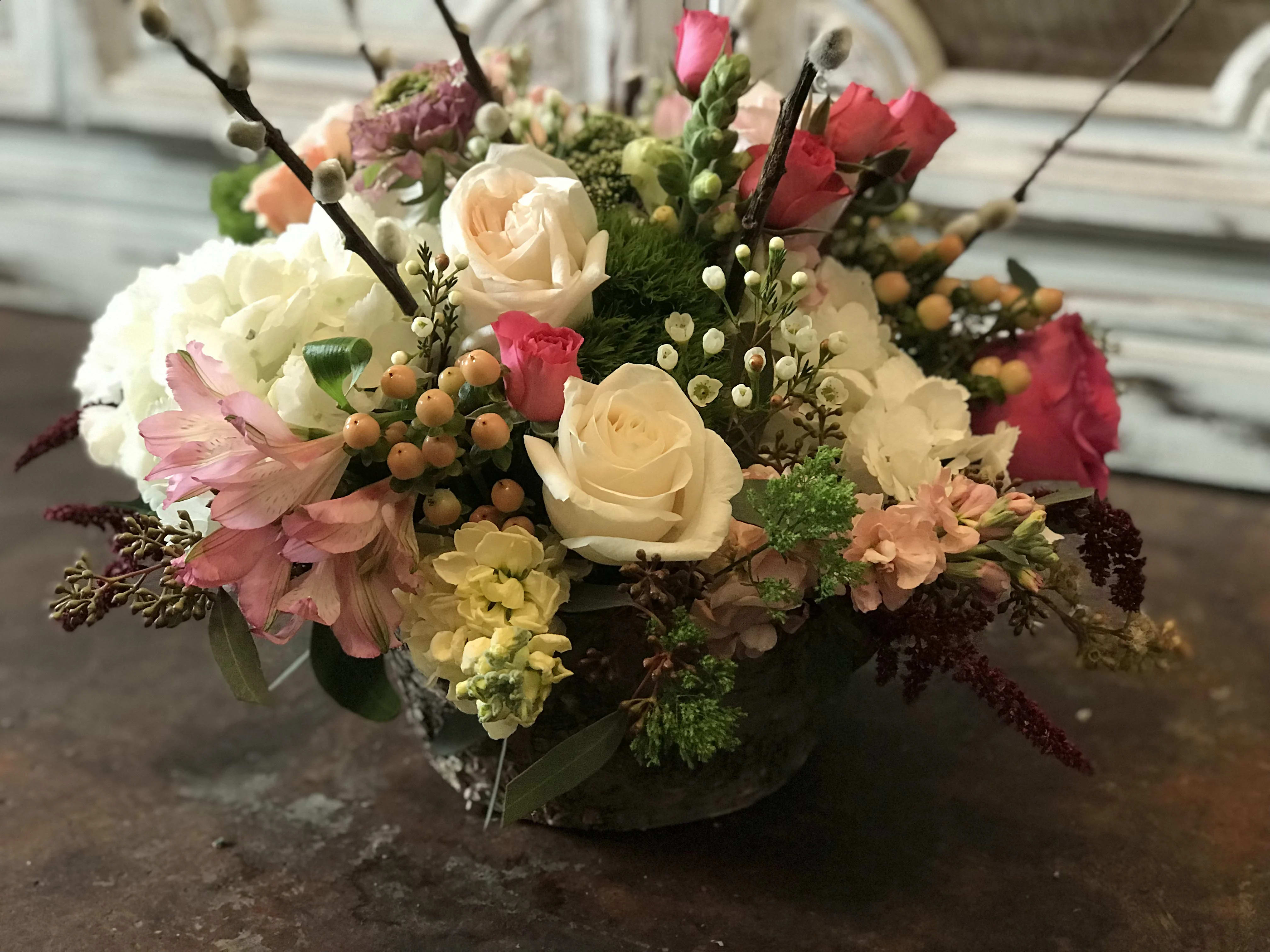 Mixed bouquet of roses, hydrangeas, and pink flowers in a low vase