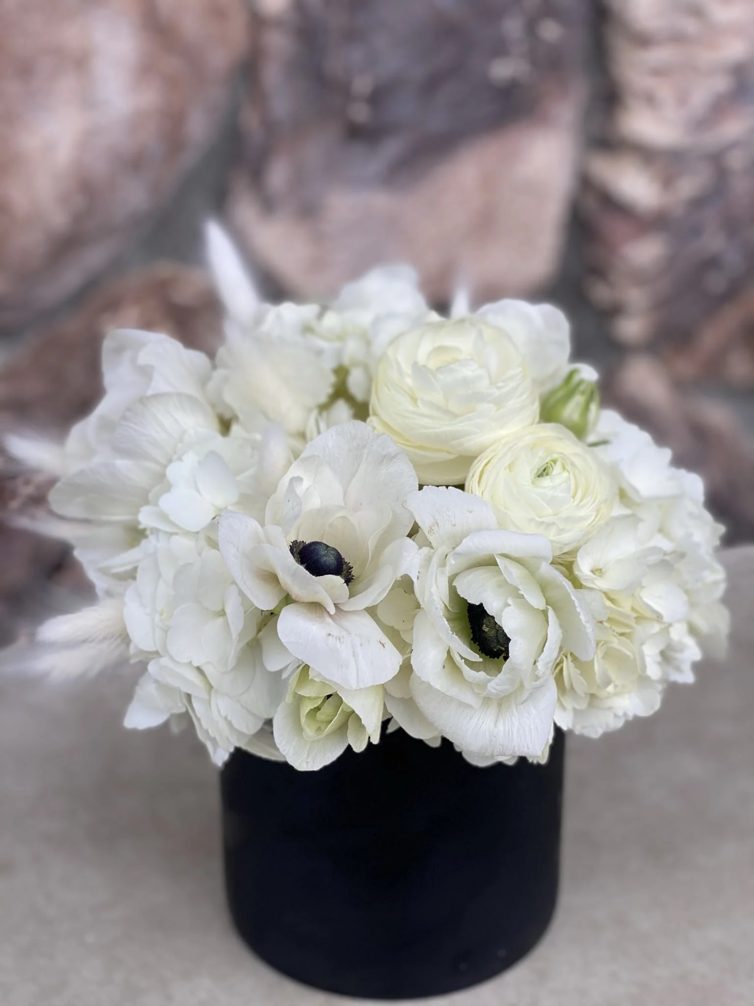 White floral bouquet in a black cylindrical vase
