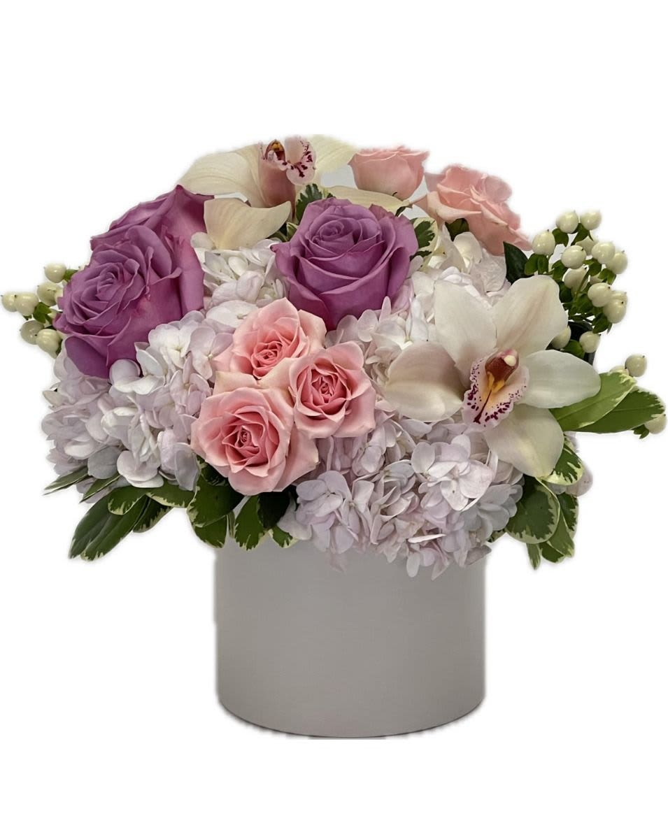 Low pastel arrangement of lavender and pink roses, orchids, and hydrangeas in a white cylinder vase