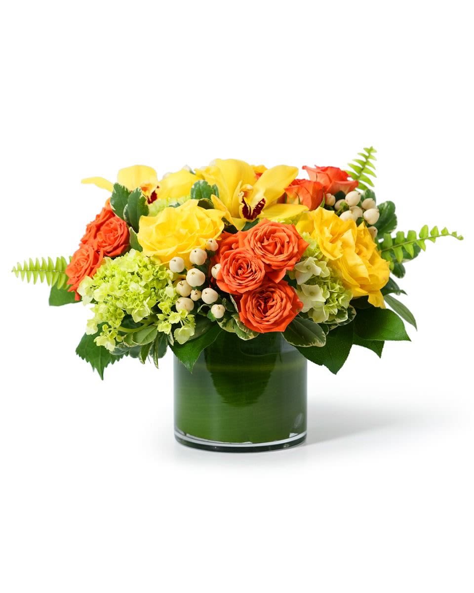 Low arrangement of yellow orchids and roses with orange roses in a green-lined glass cylinder vase