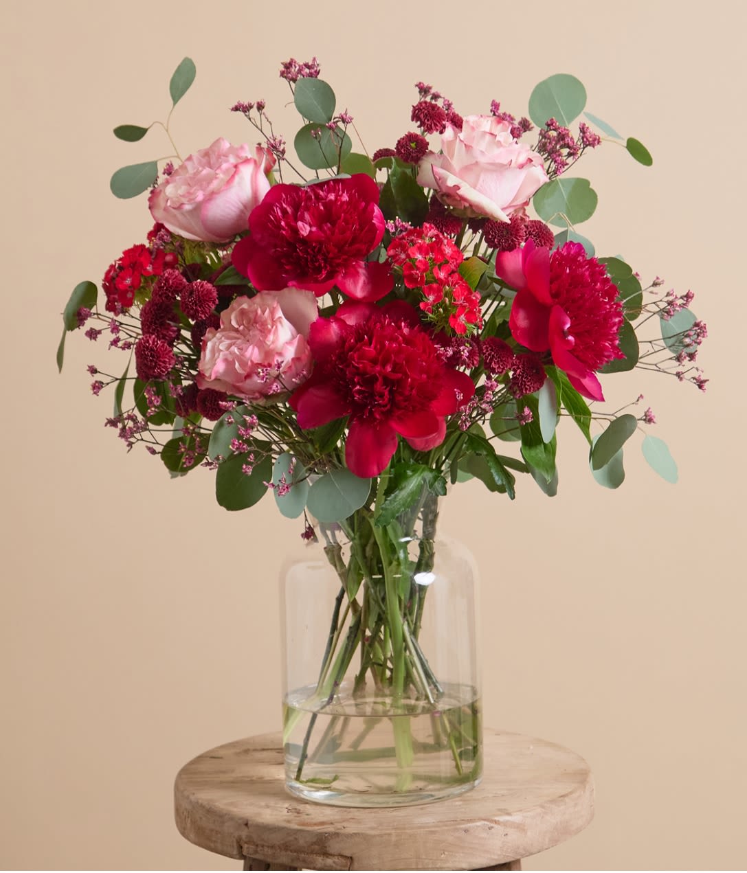 Mix Red Peonies bouquet  - A lacquered artwork in deep shades of red, this arrangement heroes large, glossy peonies among vibrant crimson dianthus, santinis, and limonium, framed by glistening eucalyptus.Red peonies symbolize love, honor, and romance. This bouquet is a powerful expression of deep affection and admiration, ideal for heartfelt occasions and grand romantic gestures.
