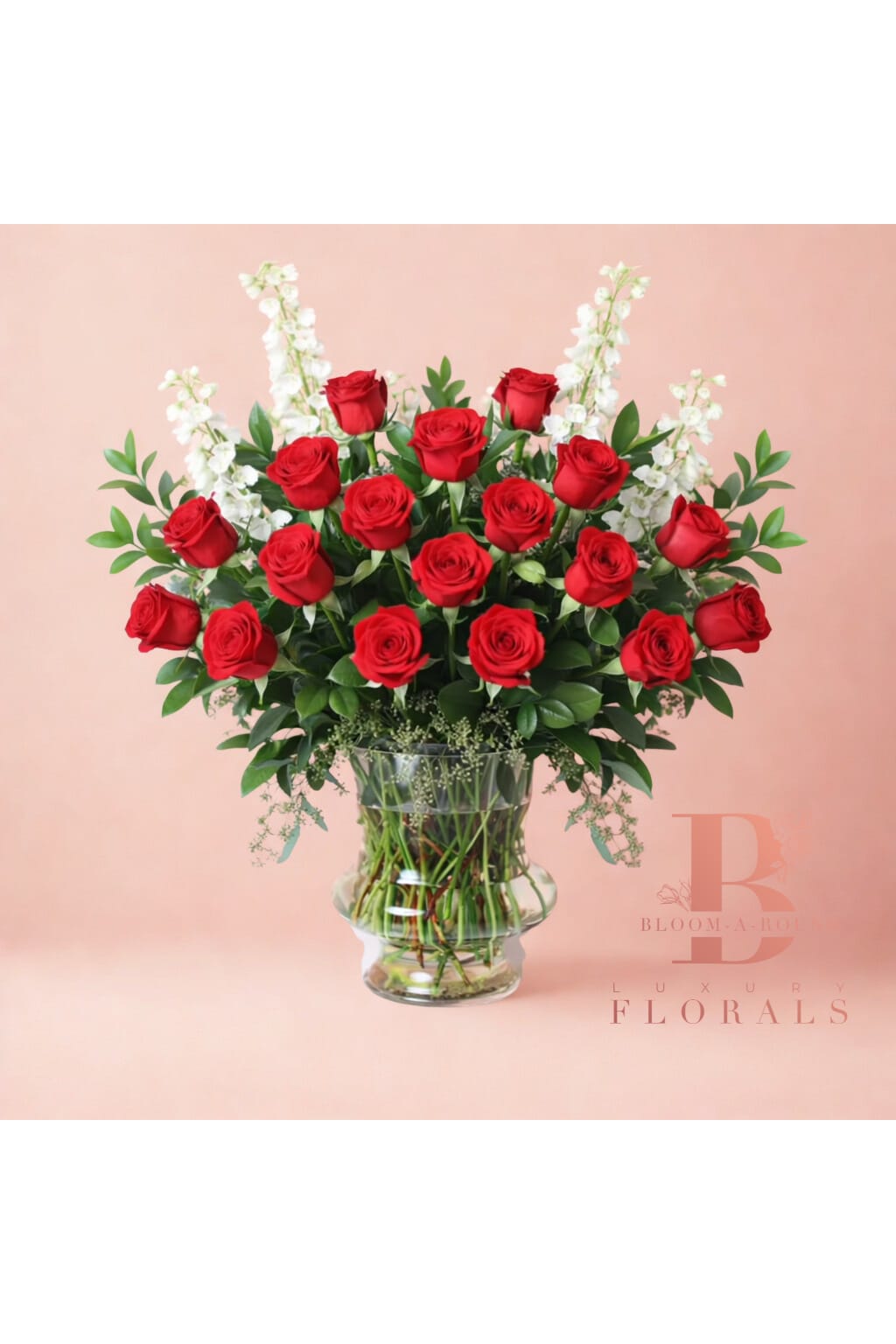 Red roses arranged in a clear glass vase with white accent flowers