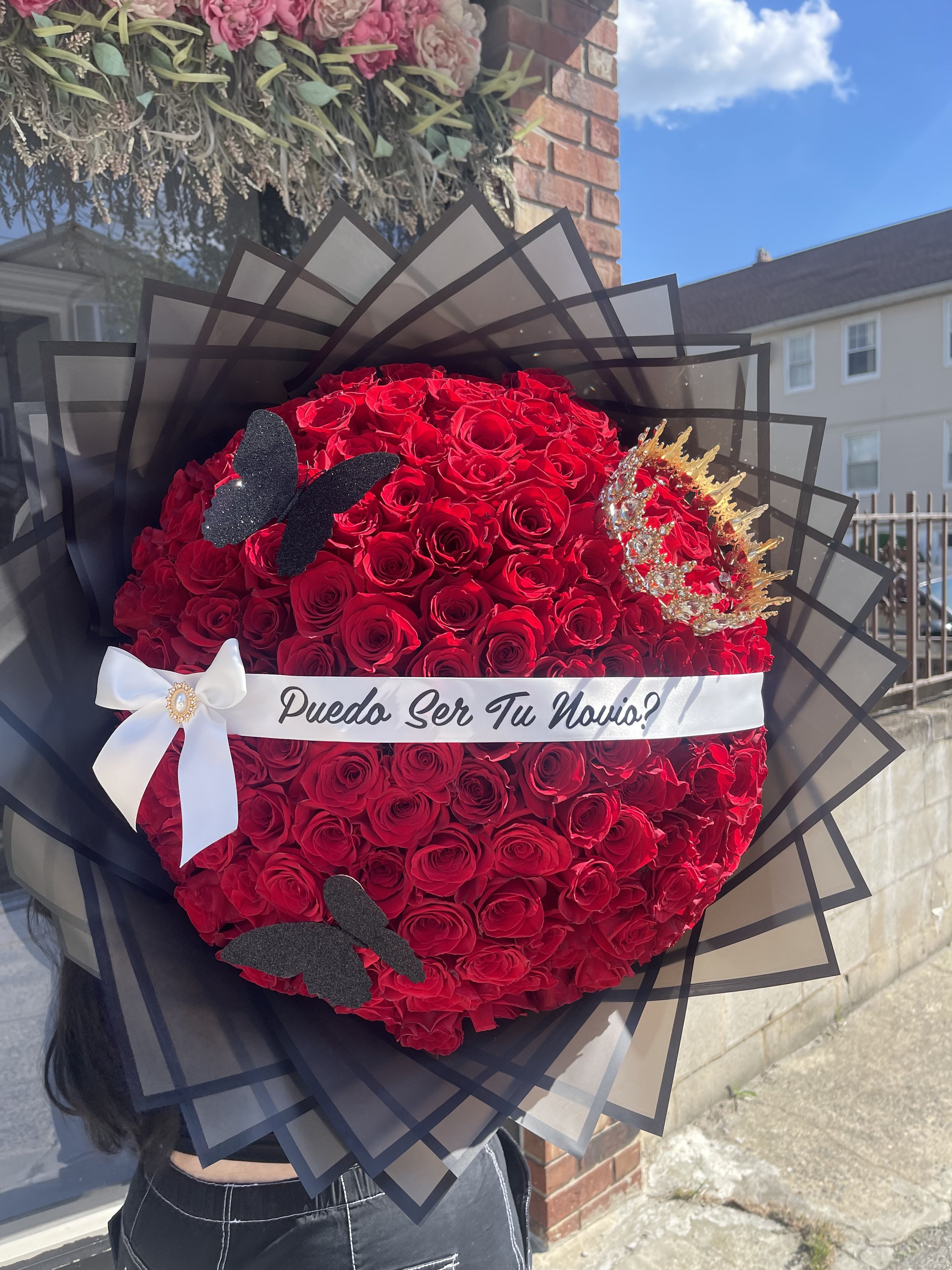 Large bouquet of red roses with a white ribbon and black wrap
