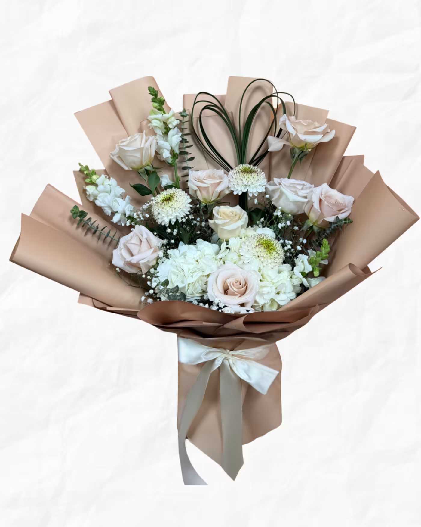 Bouquet of pale roses and white flowers wrapped in tan paper with a ribbon