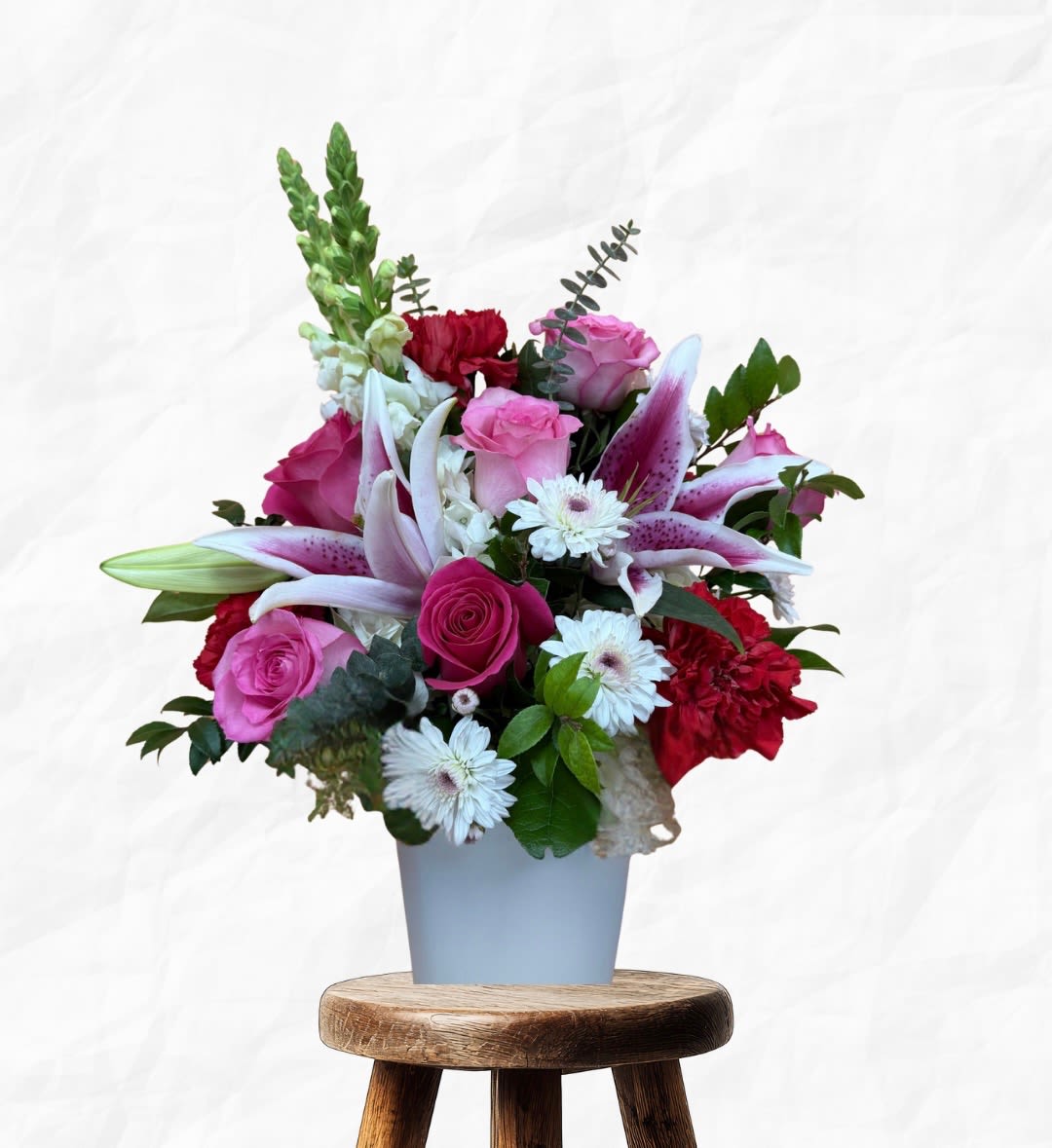 Pink and red floral arrangement in a light blue vase