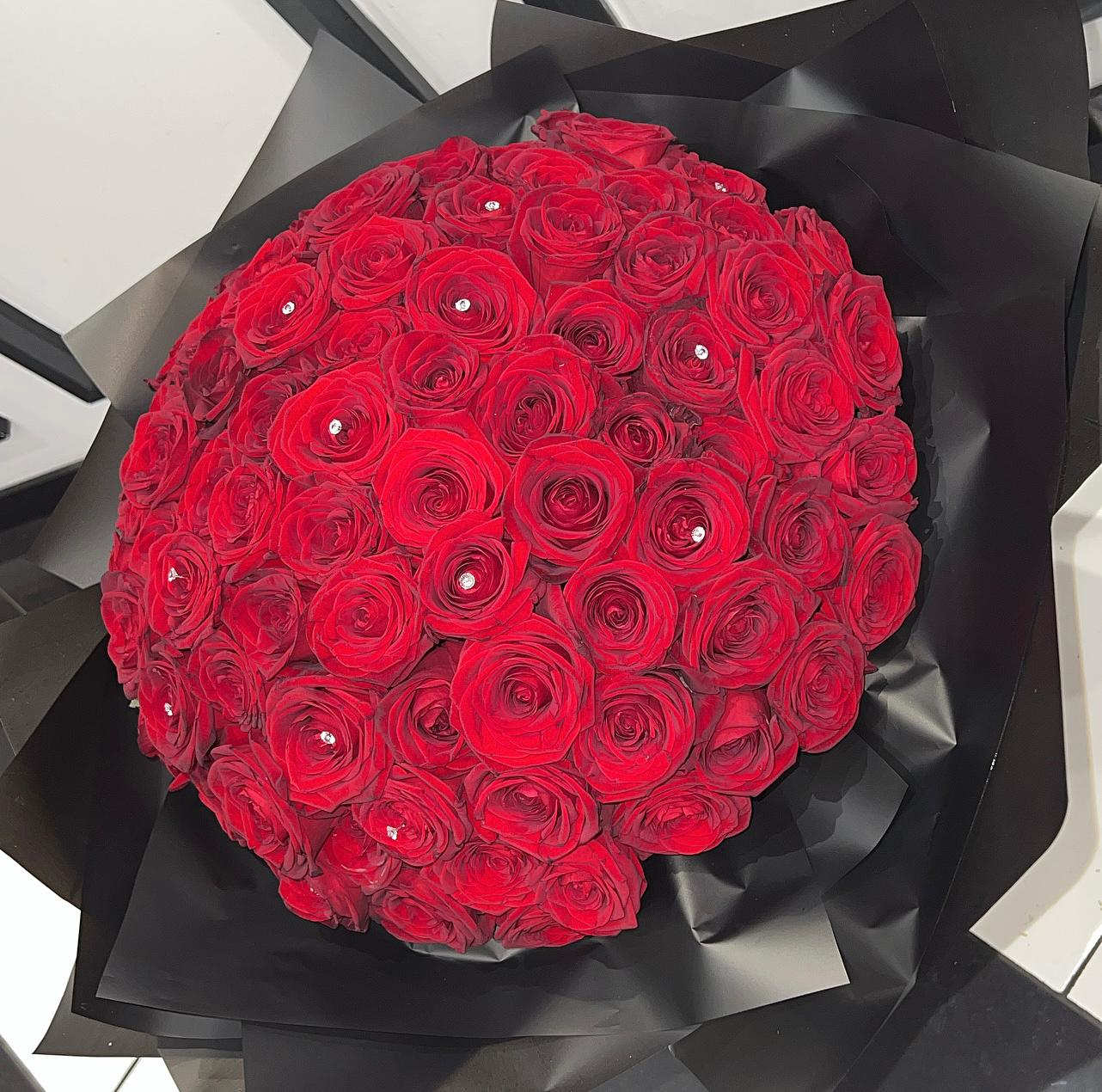 Round bouquet of red roses wrapped in black paper