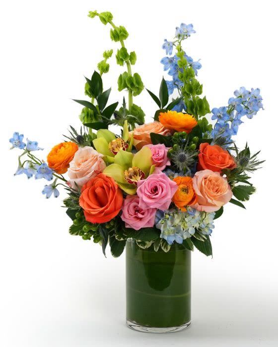 Bright mixed bouquet of roses, orchids, and hydrangea in a clear glass cylinder vase