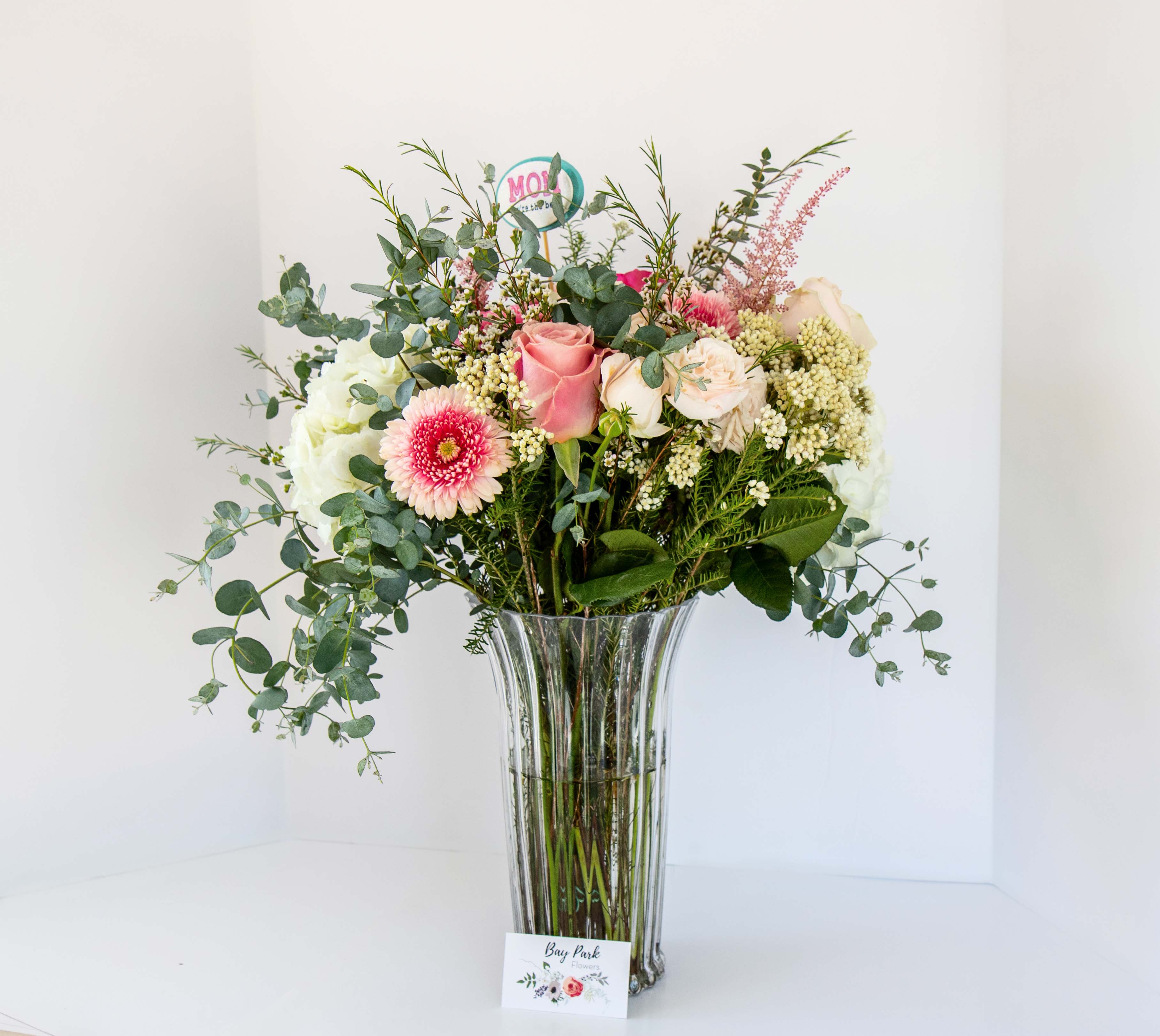 Bountiful Beauty - Beautiful blooms nestled in a generous amount of parvifolia and gravelia. Flowers include, but not limited to, mini gerbera daisies, roses, snap dragons and many other hidden gems.