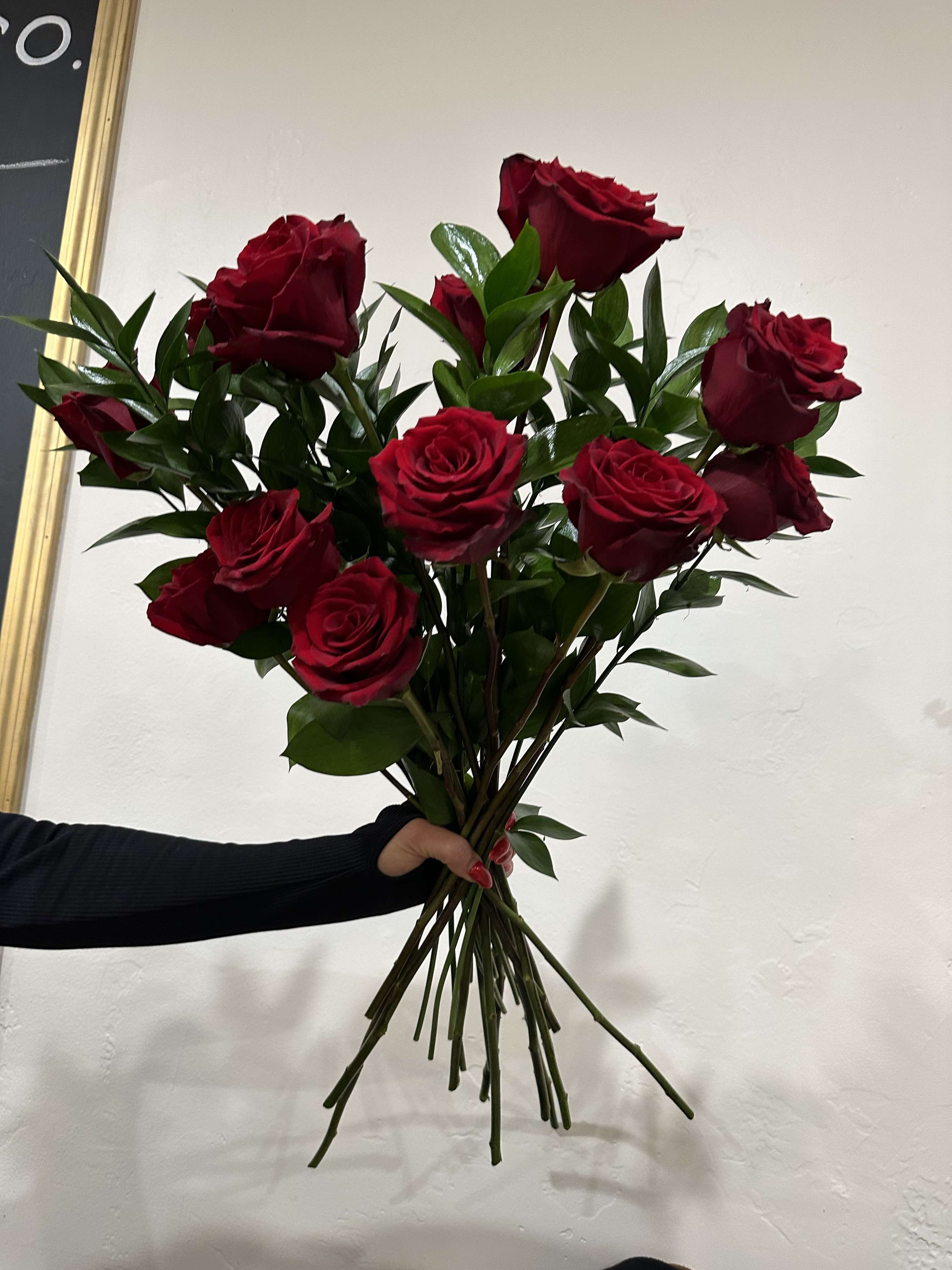 Handheld bouquet of red roses with greenery