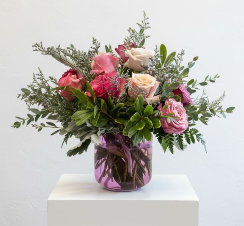 Rosé Garden Reverie - Romantic hues of blush, berry, and cream bloom beautifully in Rosé Garden Reverie. An effortlessly chic dozen rose arrangement styled in a modern pink glass vase. Lush, feminine, and designed to make every moment feel a little more special.
