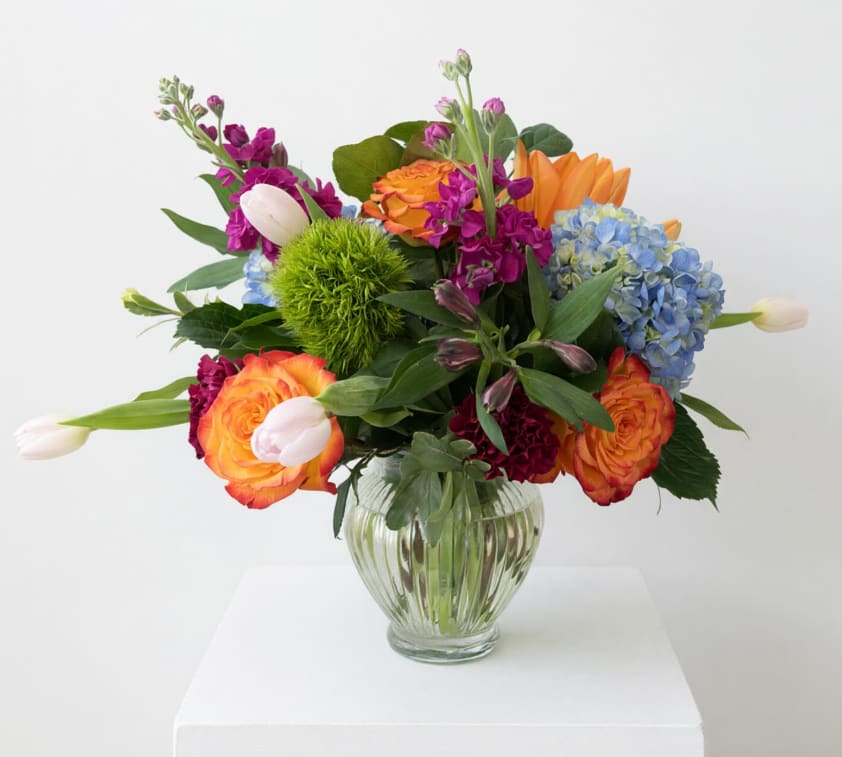 Sunset Pop Garden - Bright, bold, and bursting with joy. Sunset Pop Garden blends fiery orange roses, vibrant blue hydrangea, playful tulips, and rich jewel-toned blooms for a design that feels fresh, artistic, and full of life. A perfect pick for celebrations, birthdays, or making any day unforgettable.