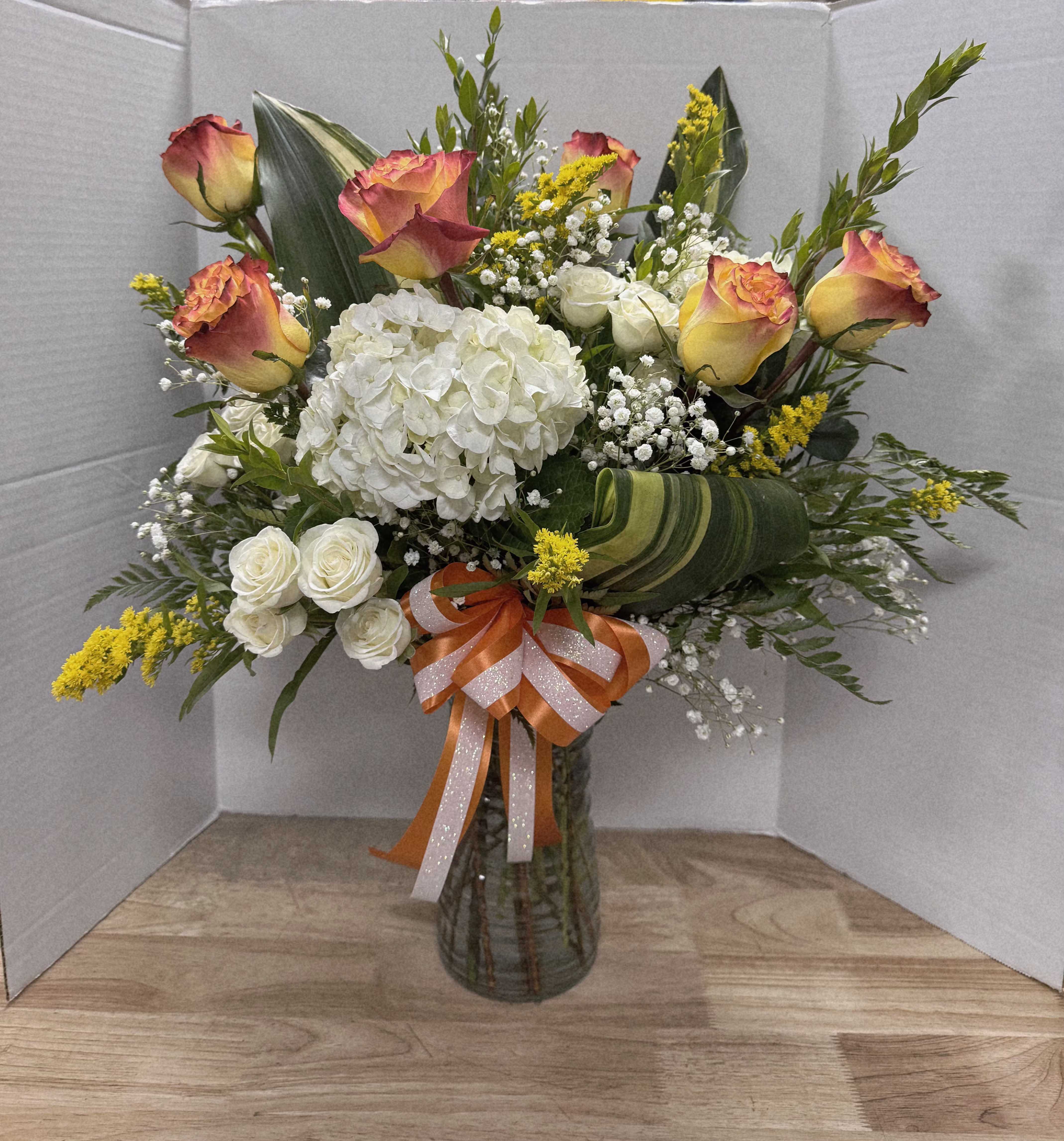 Bouquet of roses, hydrangea, and white filler flowers in a glass vase