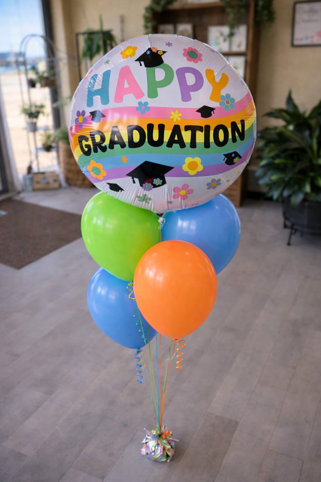 Graduation balloon bouquet with colorful latex balloons and a round "Happy Graduation" balloon