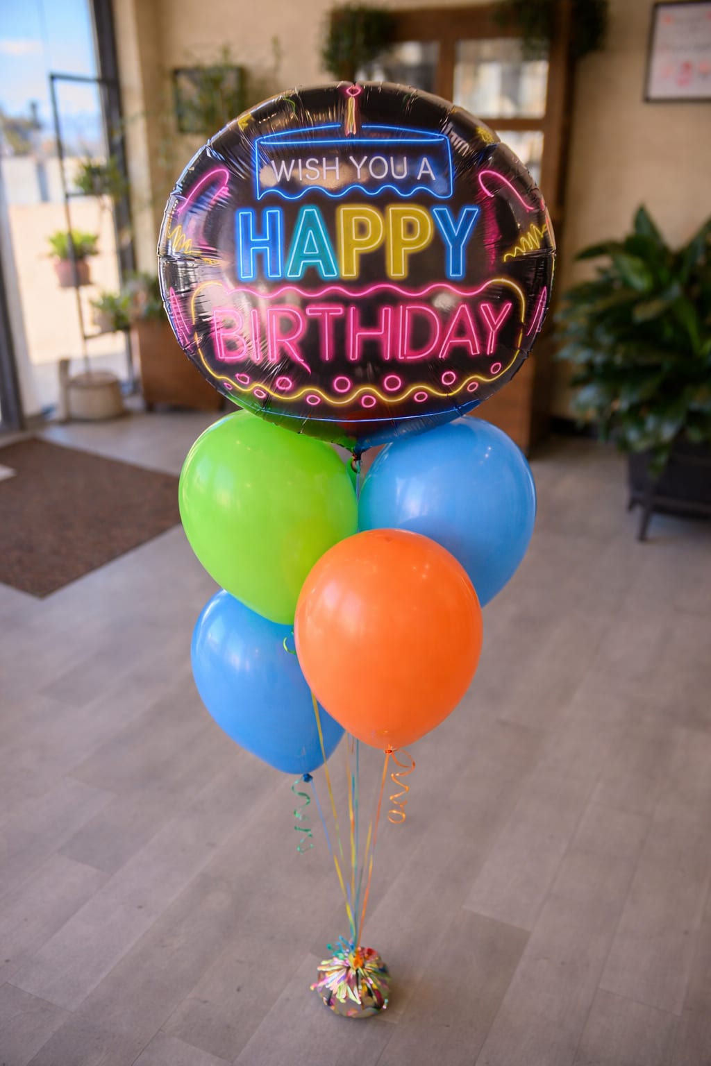 Birthday balloon bouquet with a neon-style foil balloon and colorful latex balloons