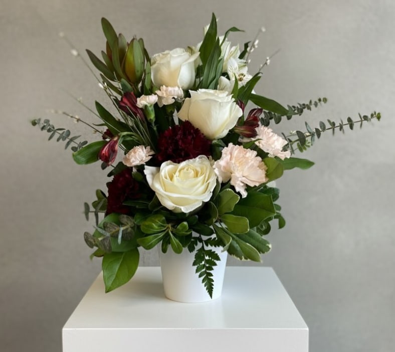 White roses and pale pink carnations in a white vase