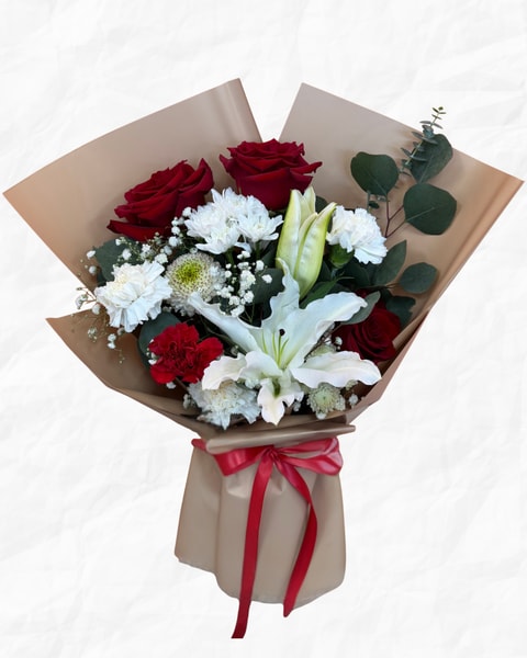 Bouquet of red roses, white lilies, and white carnations wrapped in brown paper