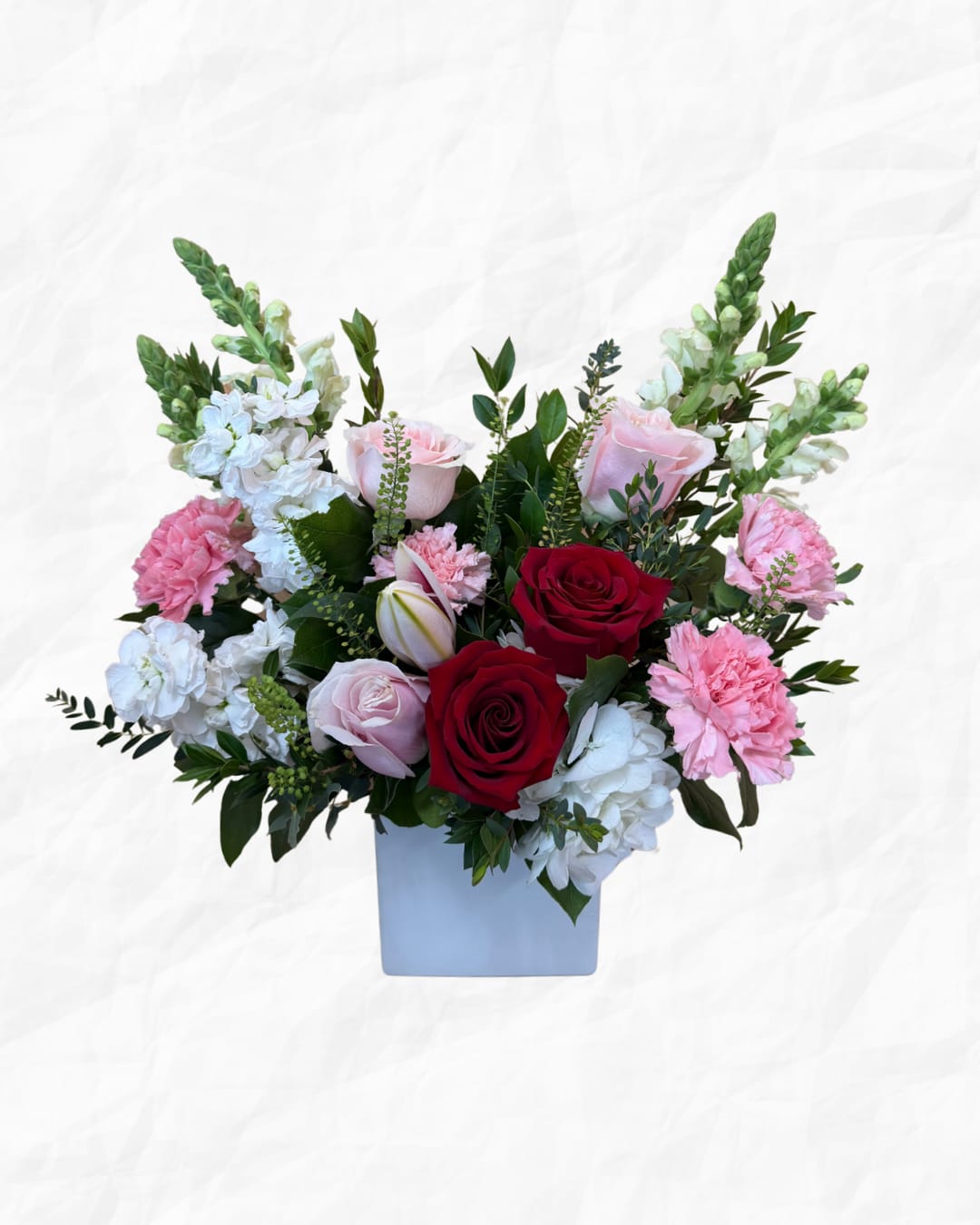 Bouquet of red, pink, and white flowers in a light blue vase