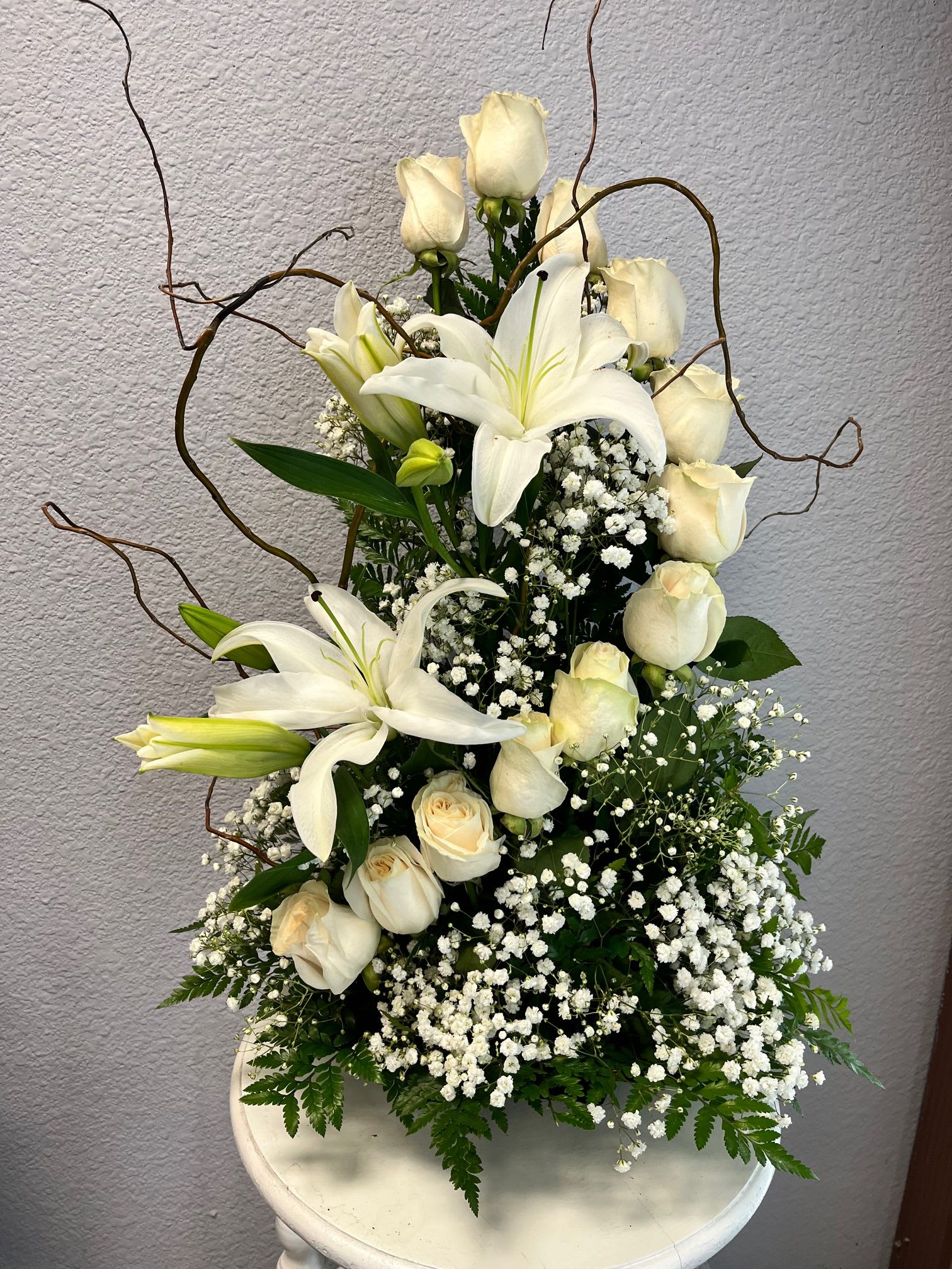 White lilies and cream roses in a white vase with baby's breath