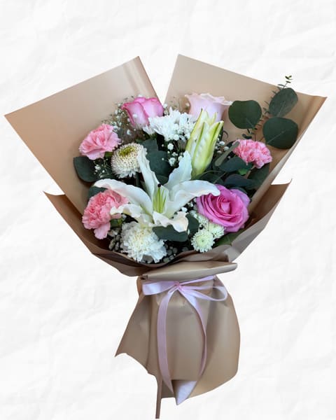 Bouquet of pink and white flowers wrapped in brown paper with a ribbon
