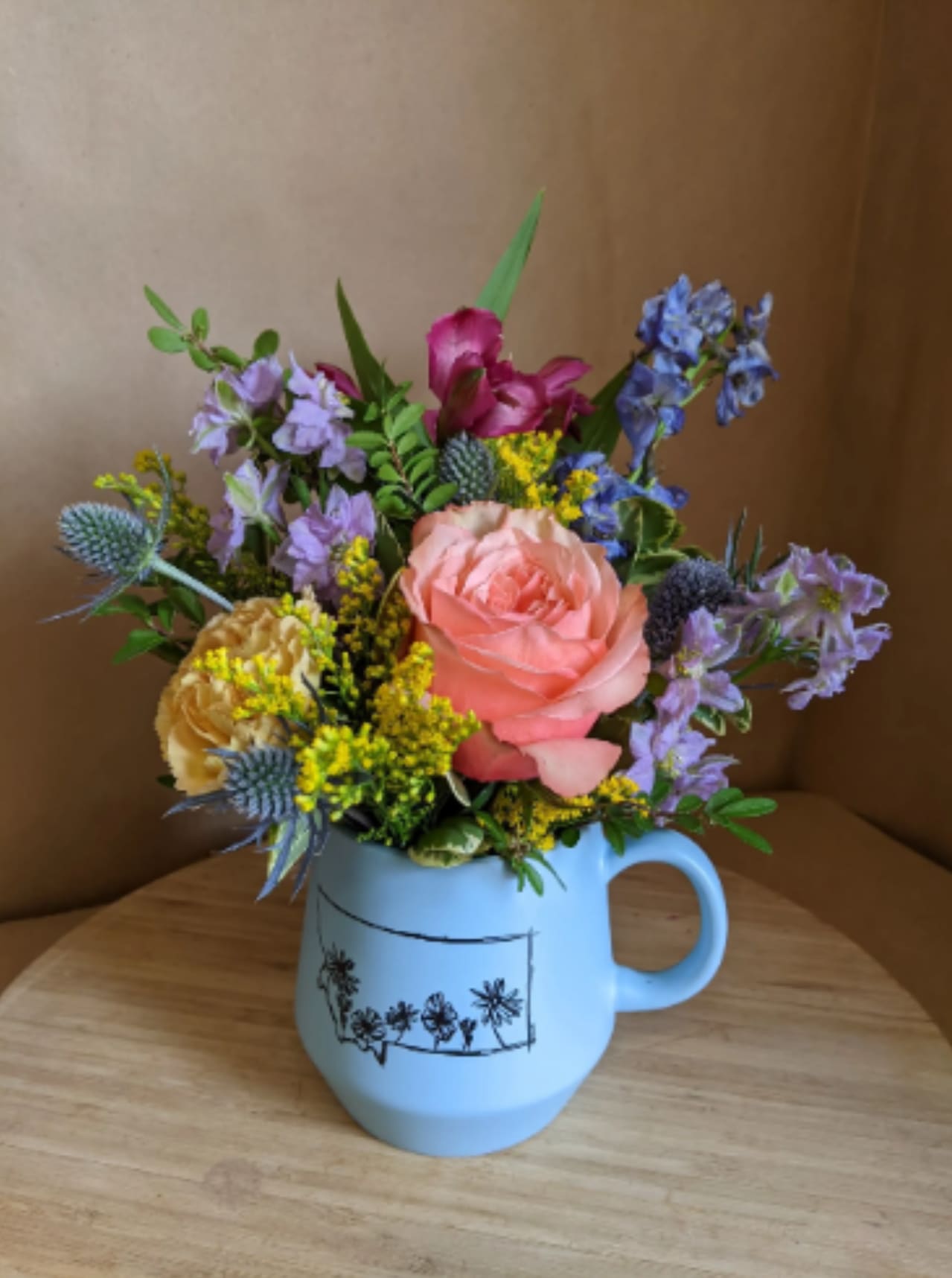 Mixed bouquet in a light blue mug-style vase