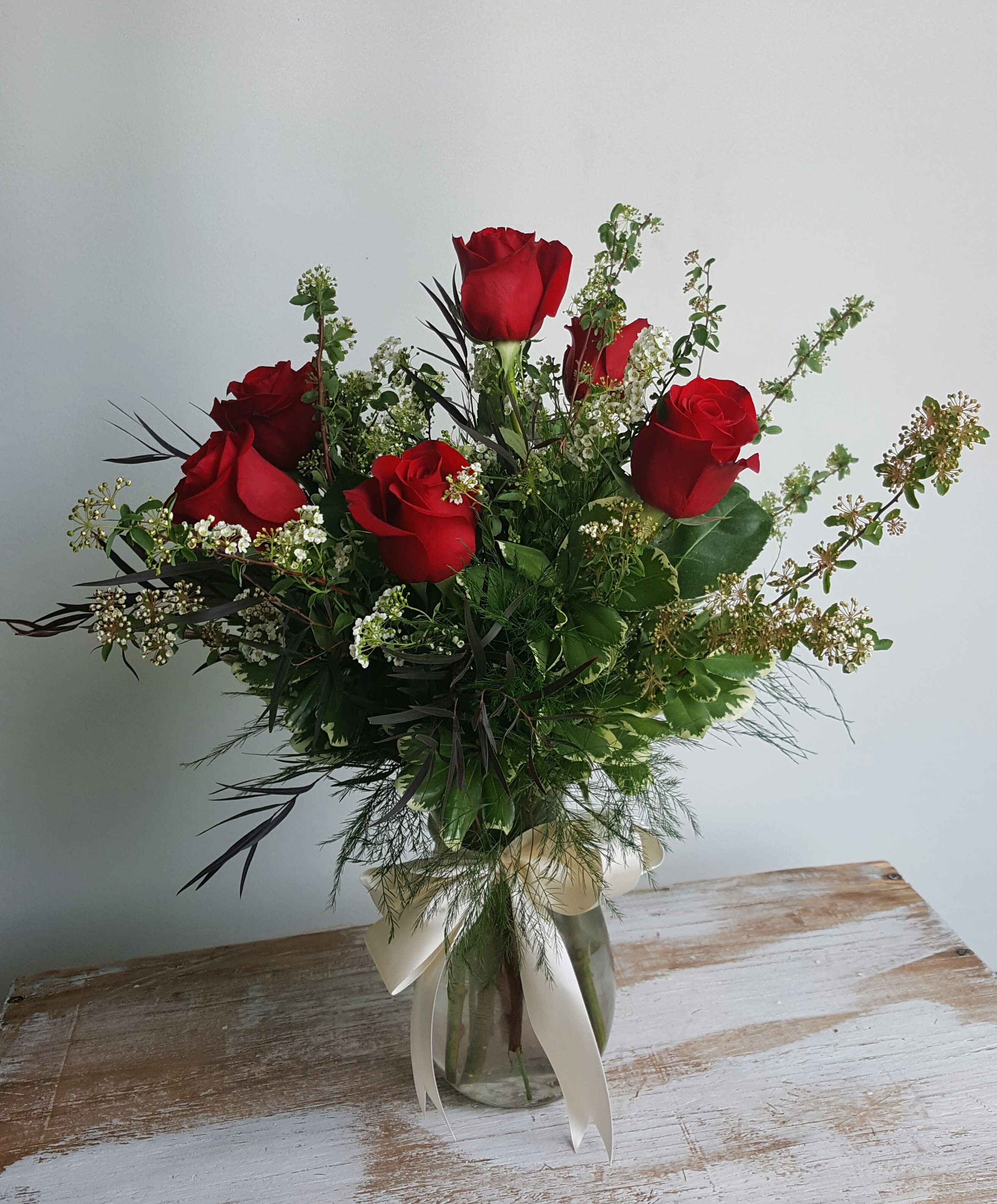 Bouquet of red roses in a glass vase with white ribbon