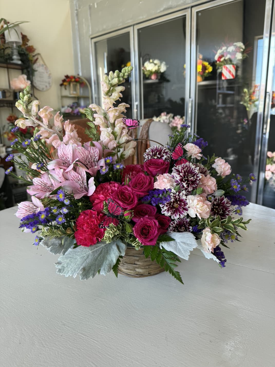 Mixed pink and purple flower arrangement in a woven basket