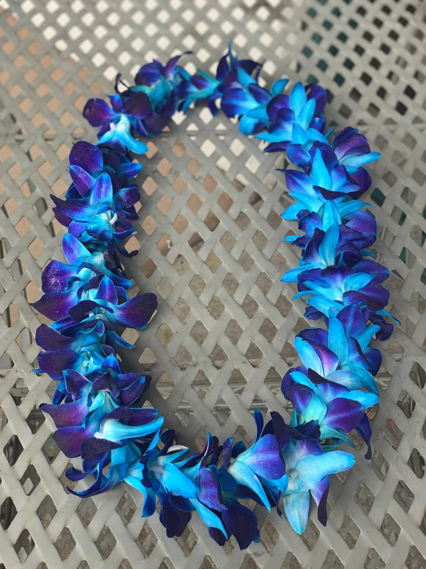 Blue and purple flower lei on a woven chair