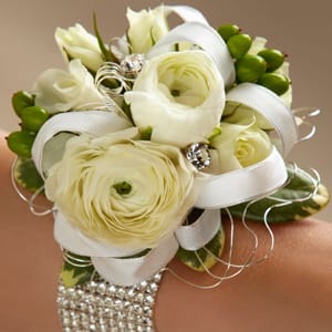 White floral wrist corsage with ribbon and rhinestone accents