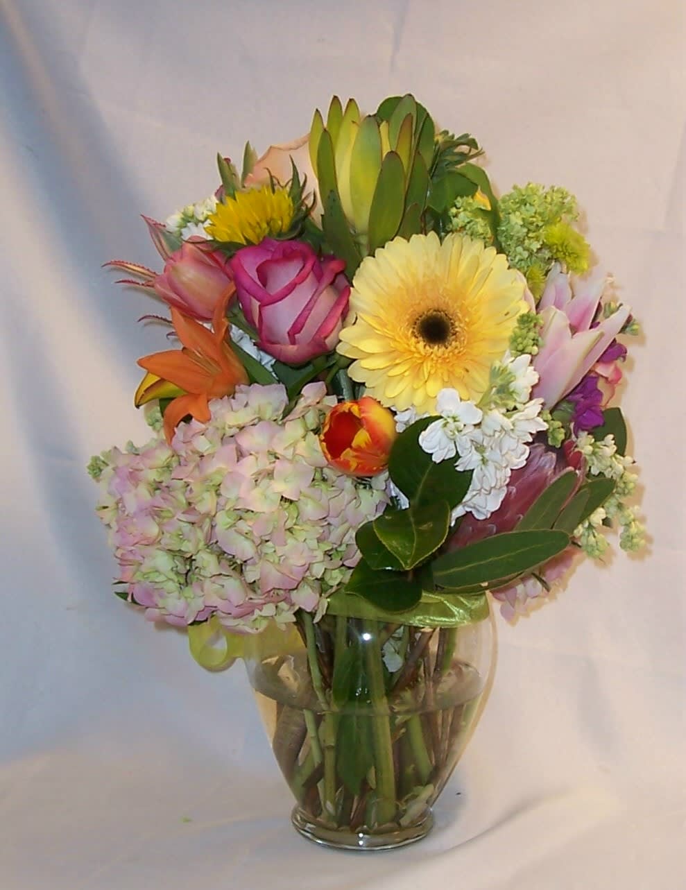 Mixed bouquet in a clear glass vase with pink, yellow, and orange blooms