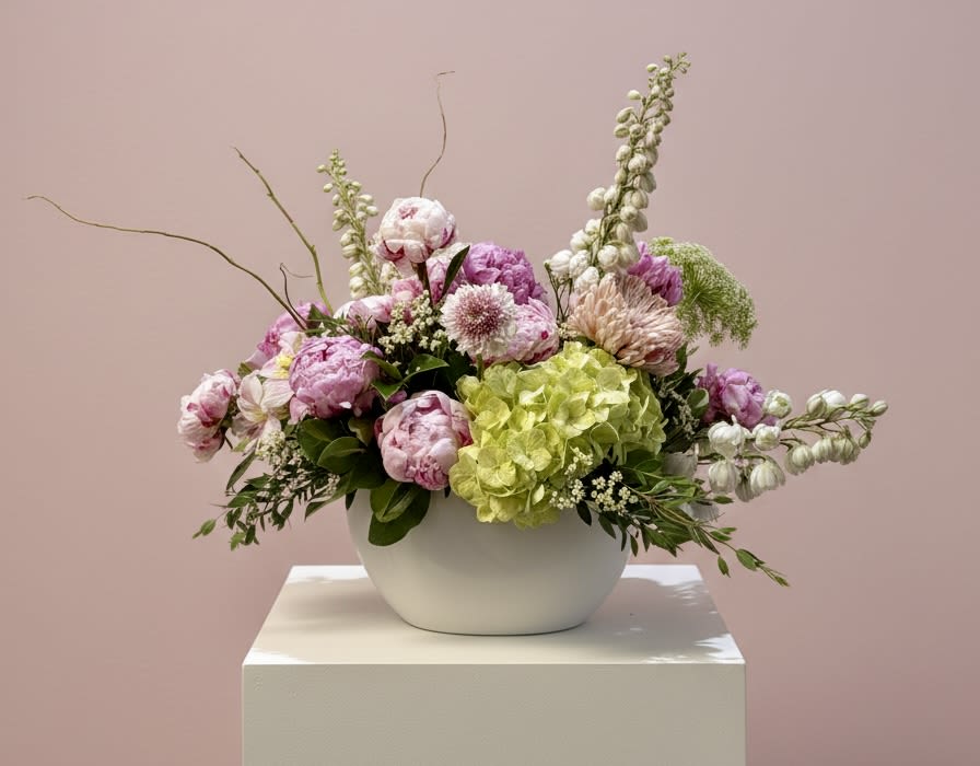 Pink and white floral arrangement in a white bowl vase