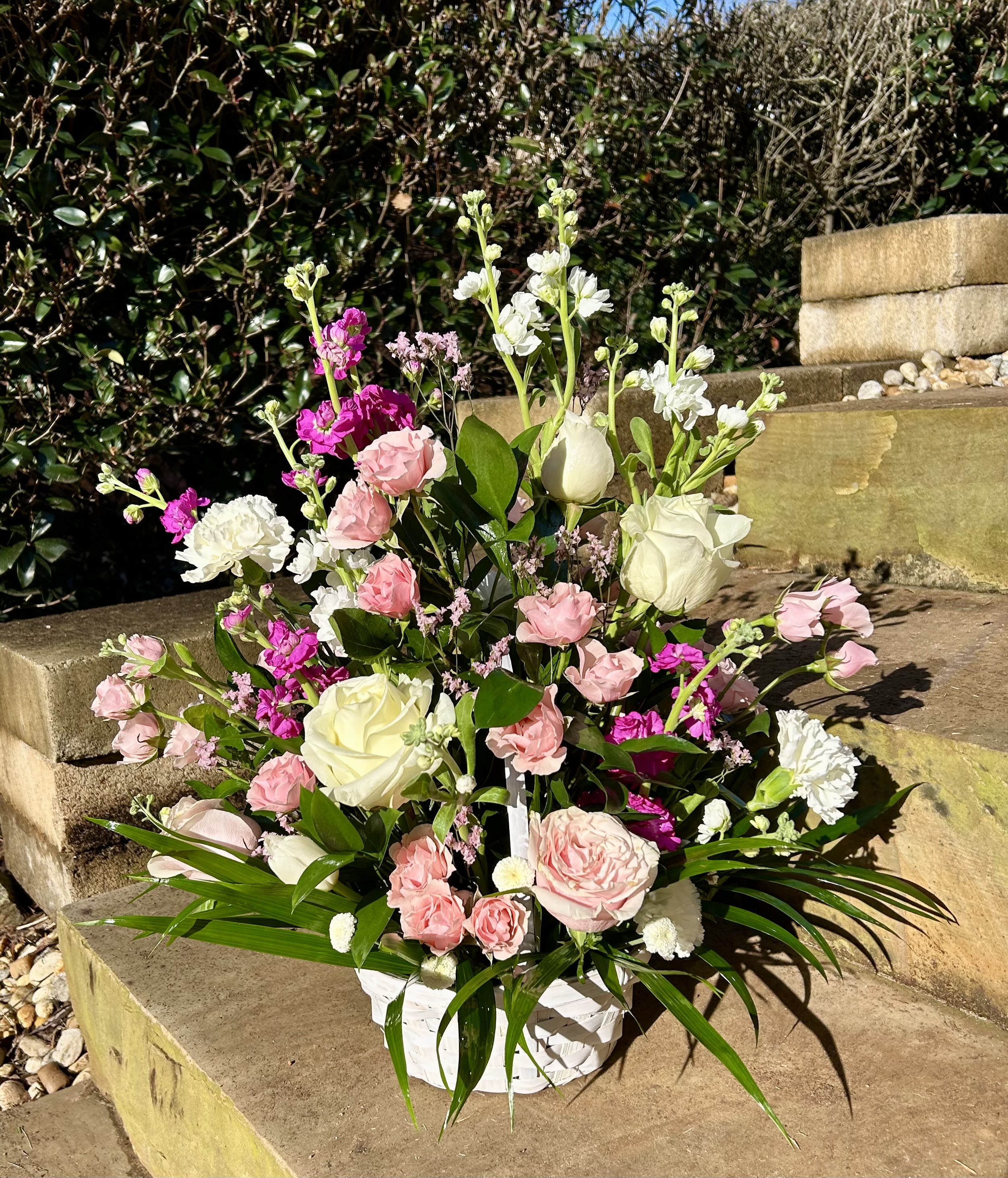 Pink and white floral arrangement in a white basket