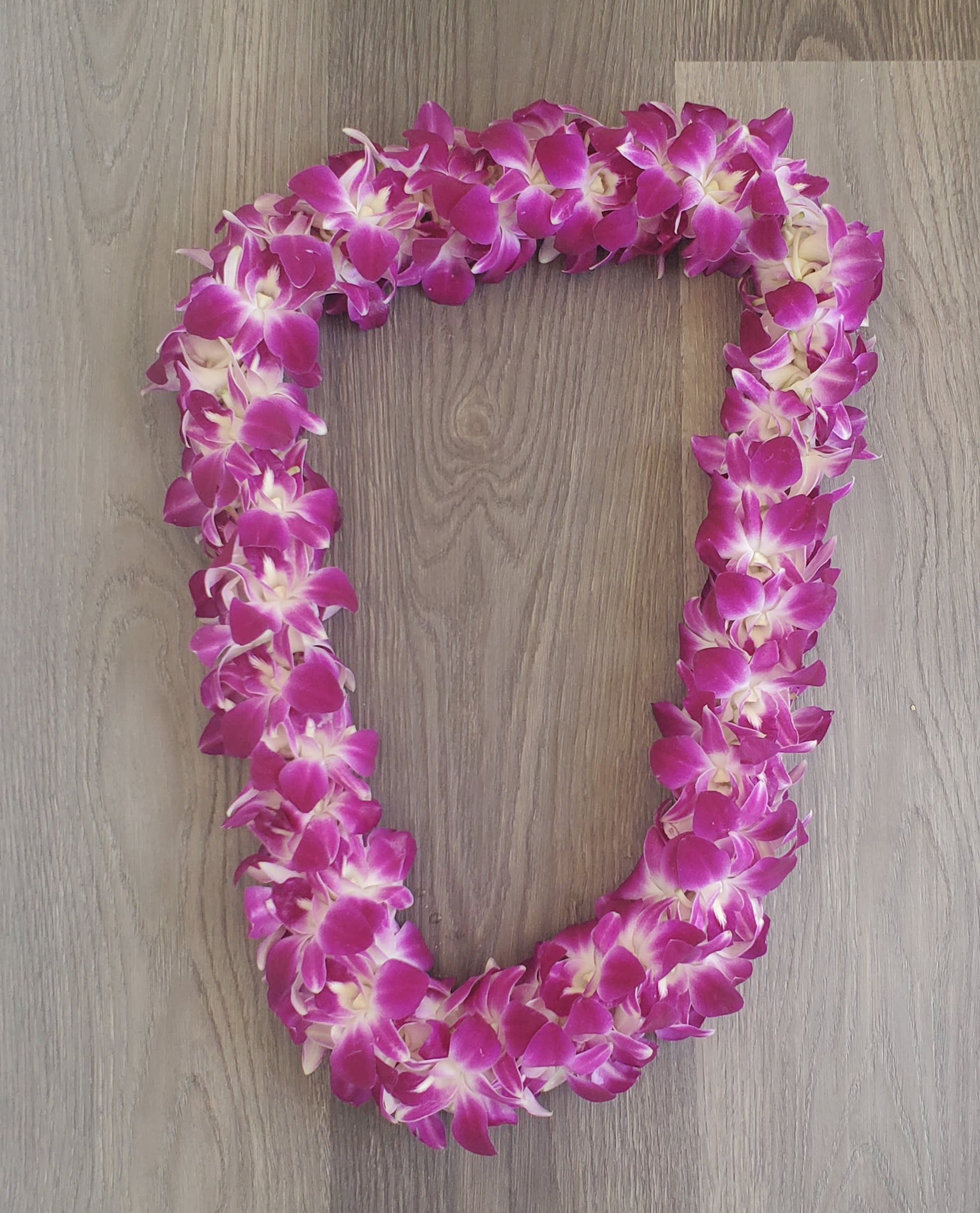 Pink orchid lei on a wood surface